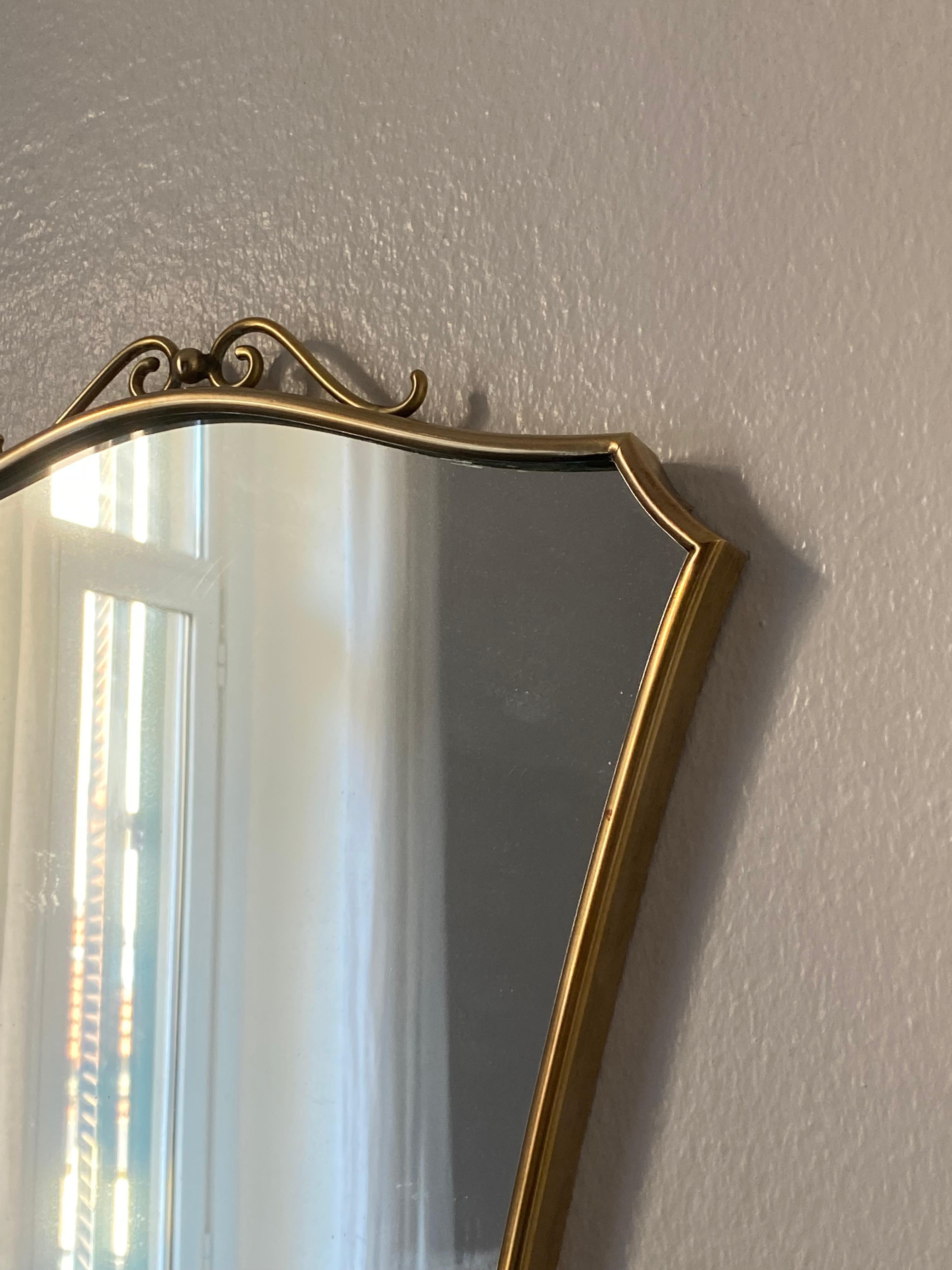 A pair of wall mirrors of intimate scale, produced in Italy, 1940s-1950s. Cut mirror glass is framed in brass. With simple modernist form and subtle ornamentation. 

Other designers of the period include Gio Ponti, Fontana Arte, Max Ingrand,