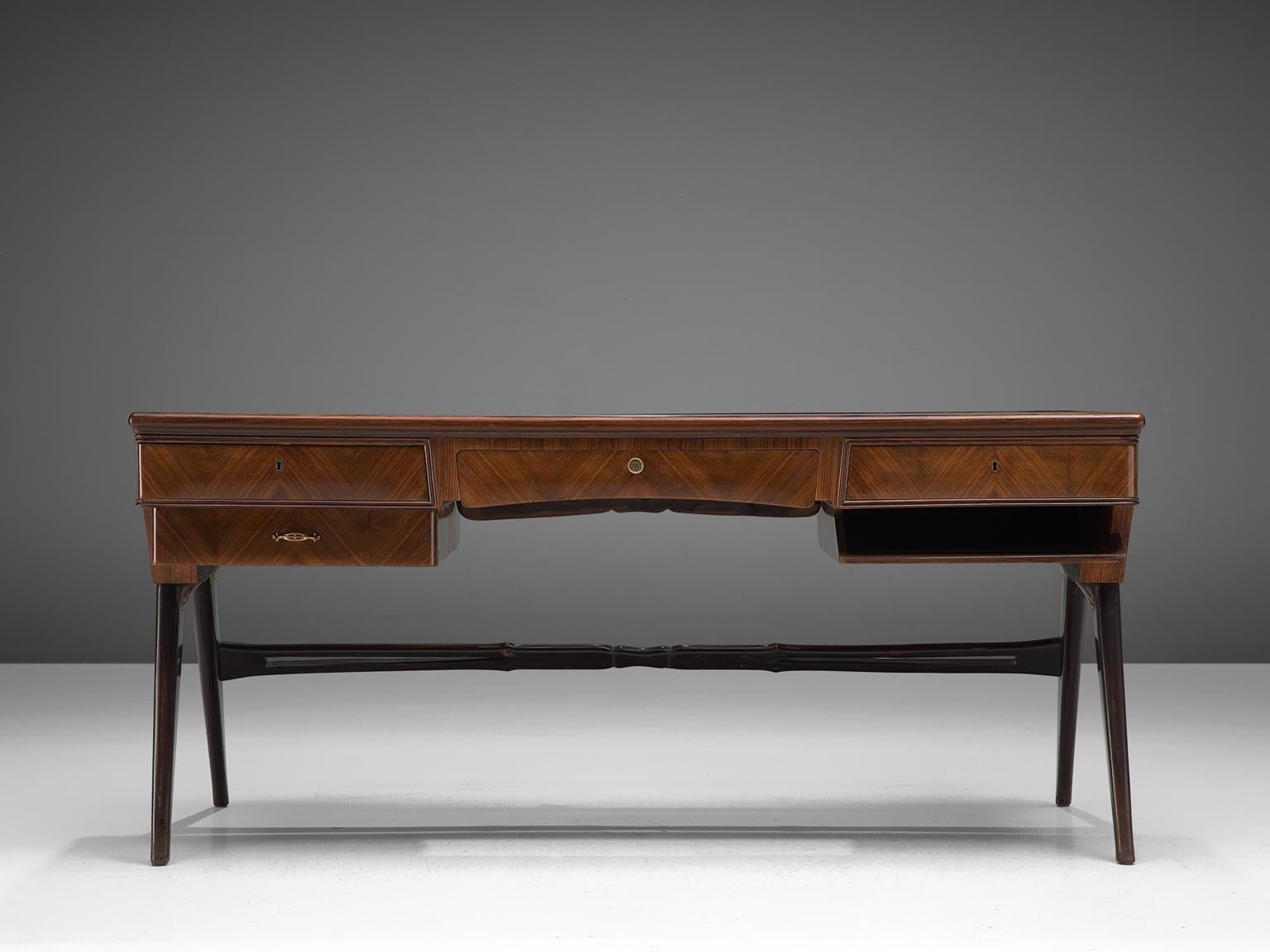 Desk, rosewood, glass, Italy, 1960s.

This desk is both refined and elegant in every way. The glass top stretches a little over the back of the solid, precisely crafted desk. This sculptural Italian piece is playful and airy. The brass feet finish