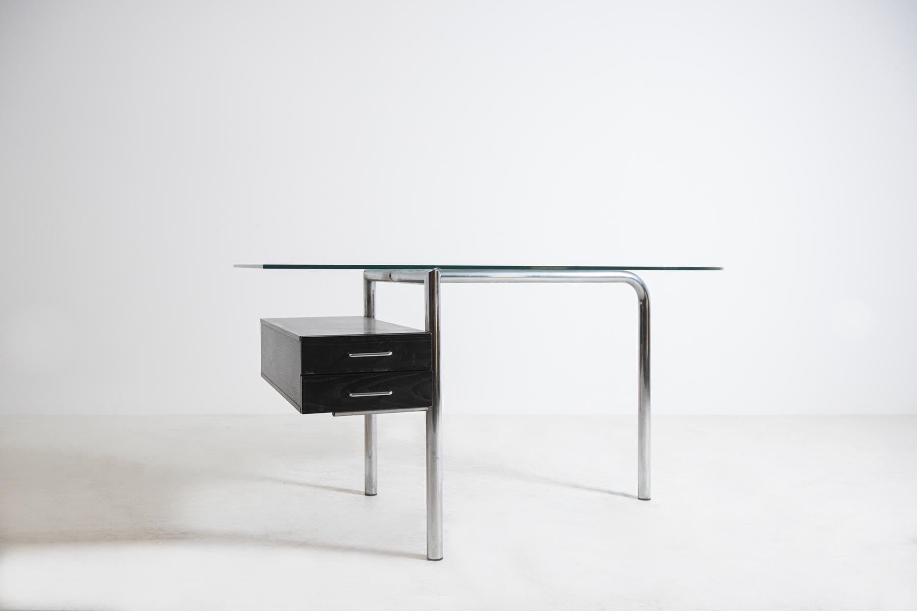 Essential Italian desk from the 1970s, in excellent condition. The desk has a tubular chrome-plated steel frame. Its top is made of thick glass with a shaped form. In the left section there are two elegant black wooden drawers. The drawers open by