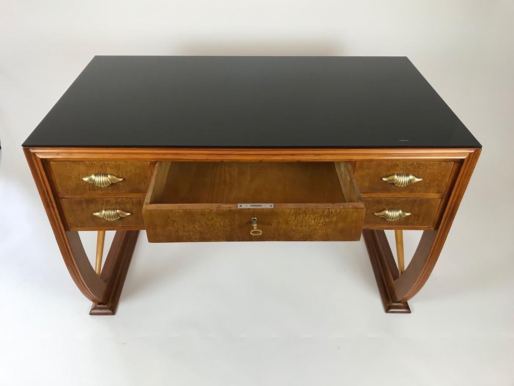 A small wooden desk or dressing table with 2 drawers and brass handles and a black glass top attributed to Paolo Buffa.