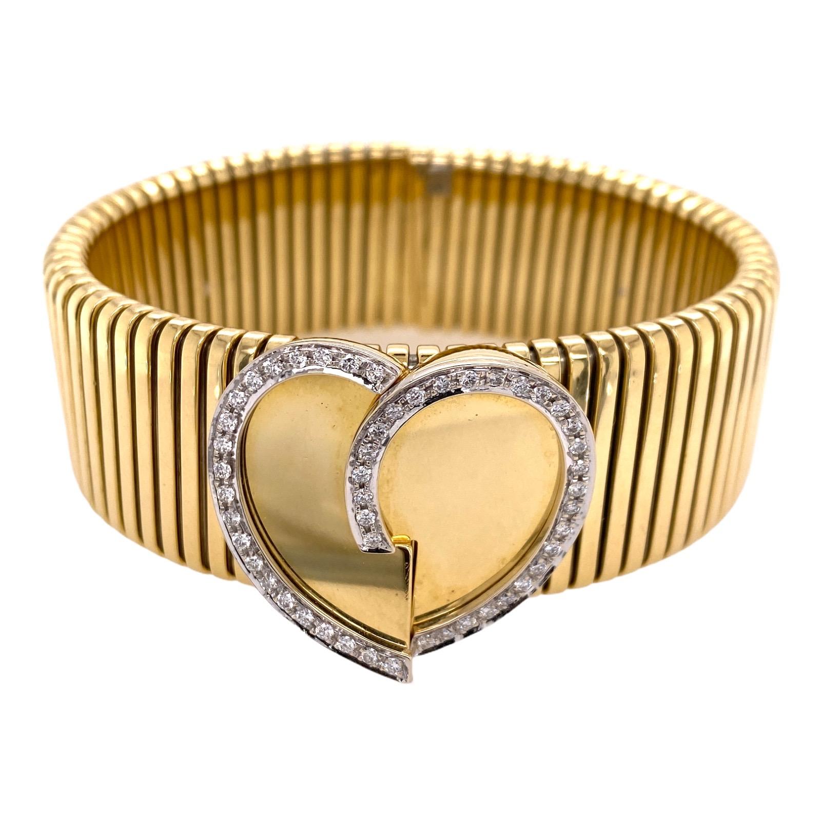Italian flexible ribbed bangle bracelet fashioned in 18 karat yellow gold. The bangle features a gold heart outlined in round brilliant cut diamonds weighing approximately .50 carat total weight. The diamonds are graded G-H color and VS clarity. The