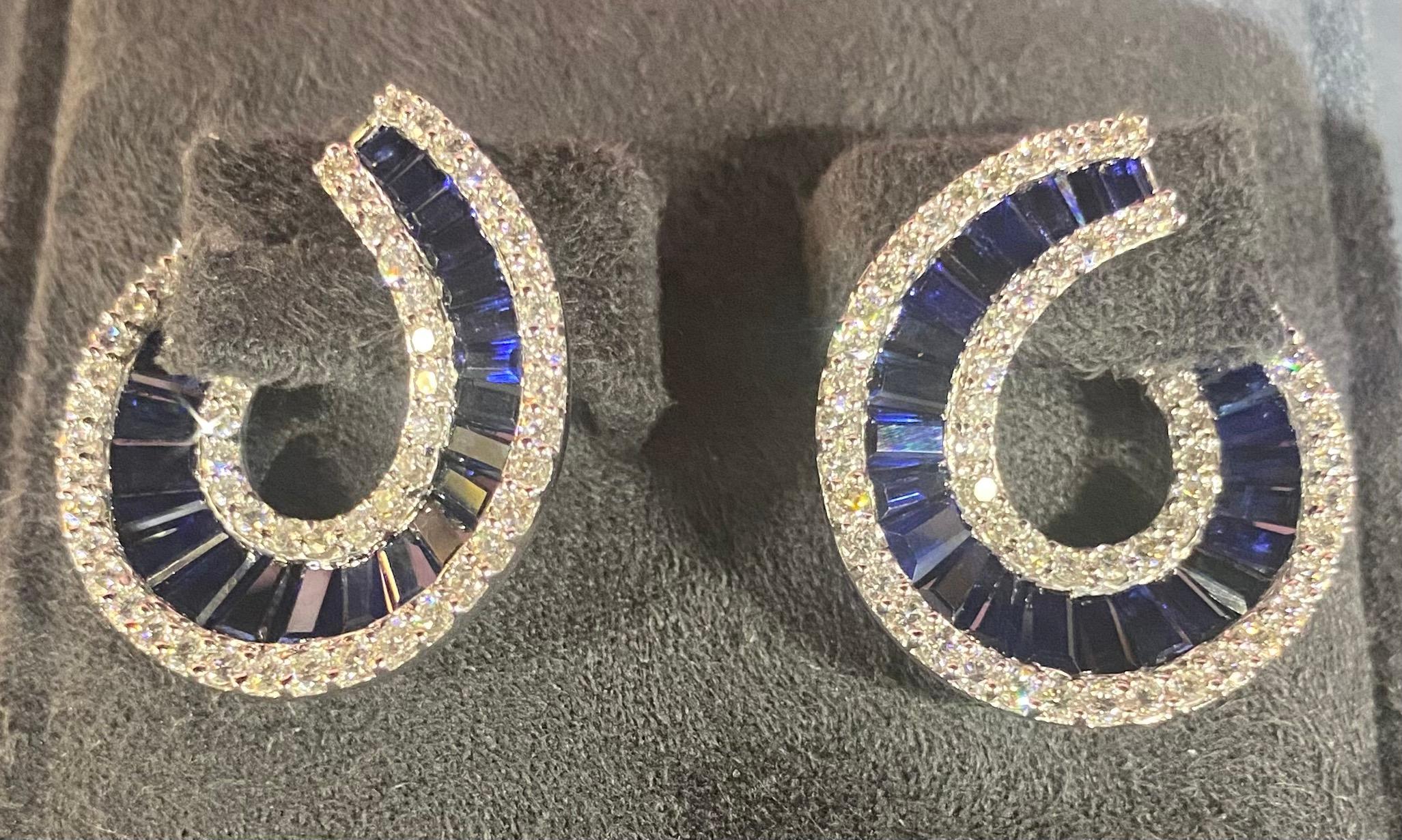 Elevate your style with these exquisite Italian round diamond and tapered baguette sapphire swirl earrings crafted in 18-carat white gold. Reflecting the renowned craftsmanship of Italian jewelry design, these earrings are a true testament to