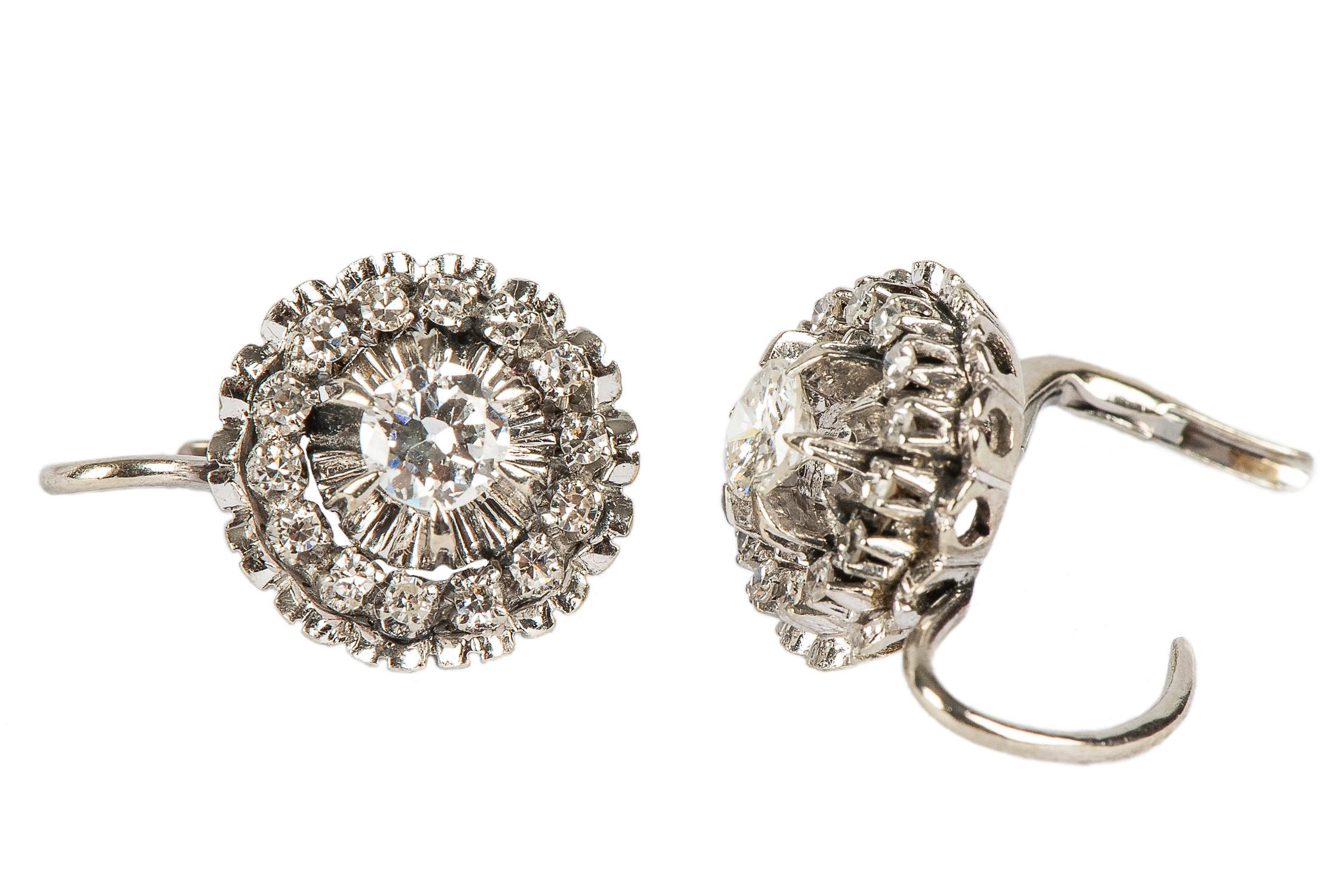 Fashioned as 18k white gold pendant earrings of stepped floral design set with two central brilliant-cut diamonds weighing approximately .76 carat total, surrounded by 28 small diamonds in a prong mounting within a crenelated outer border of white