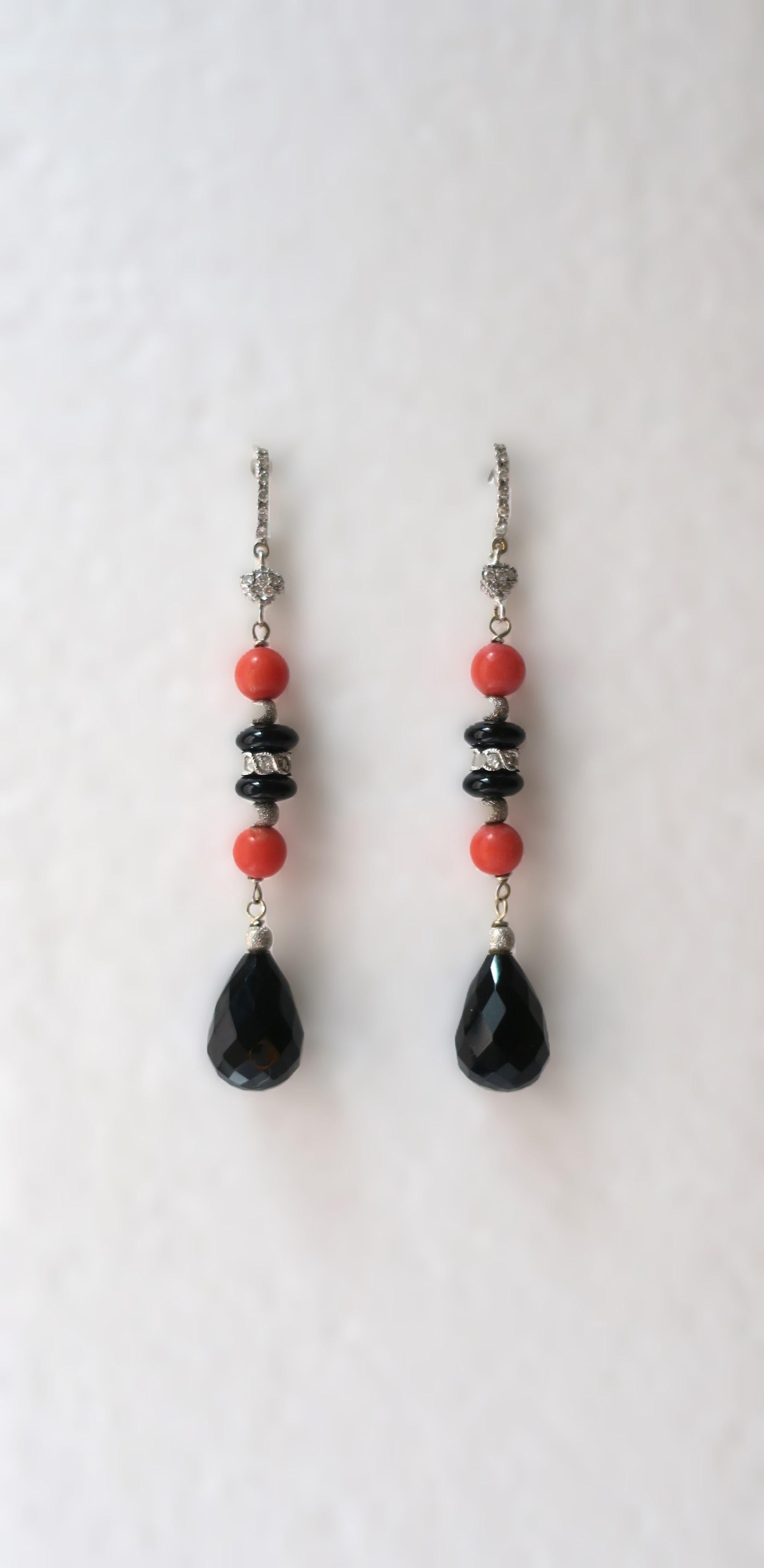 A very beautiful pair of Italian diamond, coral, black onyx, 18-karat white gold dangle earrings, circa early-2000s. Earrings are pave set diamonds, coral, and black onyx, set in 18-karat white gold. The diamonds are round brilliant cut, with