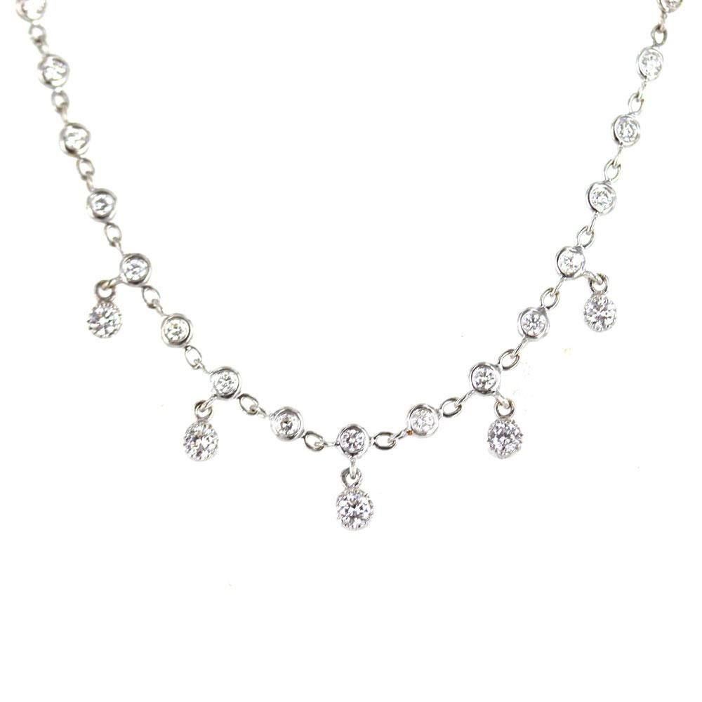 Simple elegance at its best. This stylish diamond drop necklace features bezel set round brilliant cut diamonds that total approximately 1.10 carat total weight.  The diamond drops measures .30 inches in length. Fashioned in 18 karat white gold, the