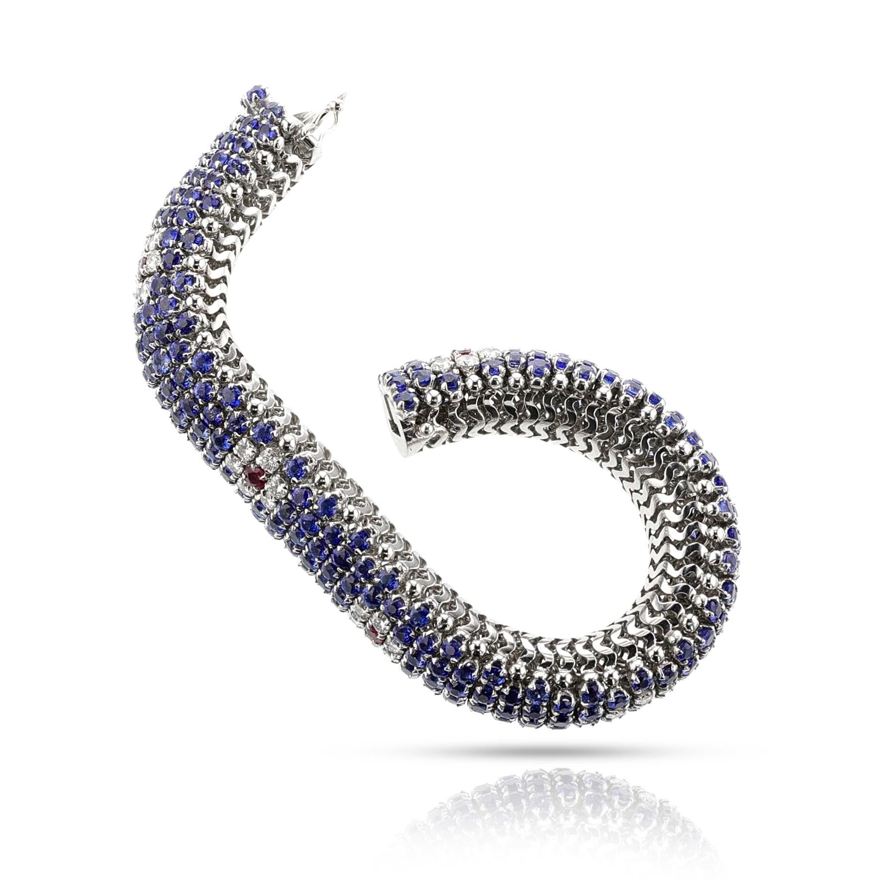 Bracelet italien en or blanc 18 carats, diamants, rubis et saphirs. Le bracelet a un design en forme de bombe. Le bracelet est orné de motifs floraux en diamant et en rubis. Les diamants pèsent environ 2,60 carats et les saphirs environ 28 carats.
