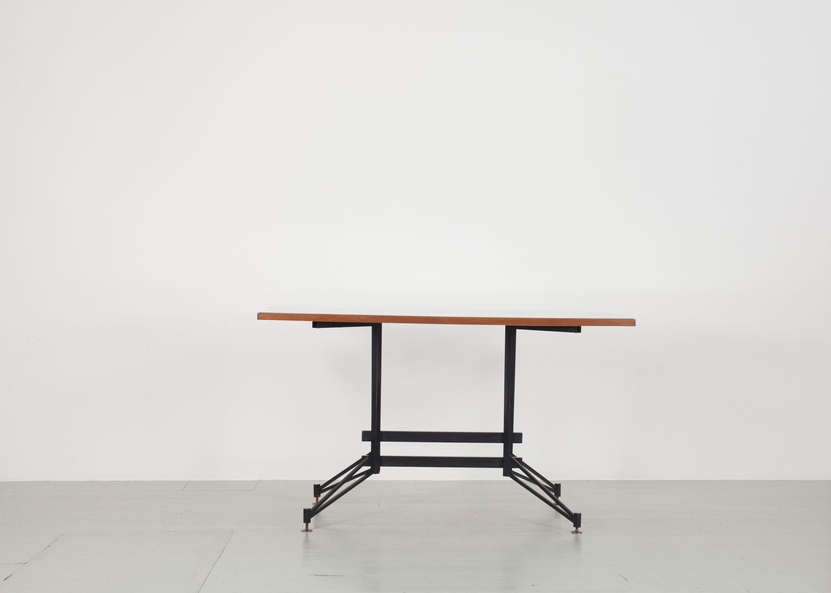 Elegante mesa italiana de los años 50 con estructura de hierro lacado en negro y tablero de diseño asimétrico con incrustación de cristal transparente. La combinación de carácter industrial y detalles refinados confiere a la pieza un atractivo