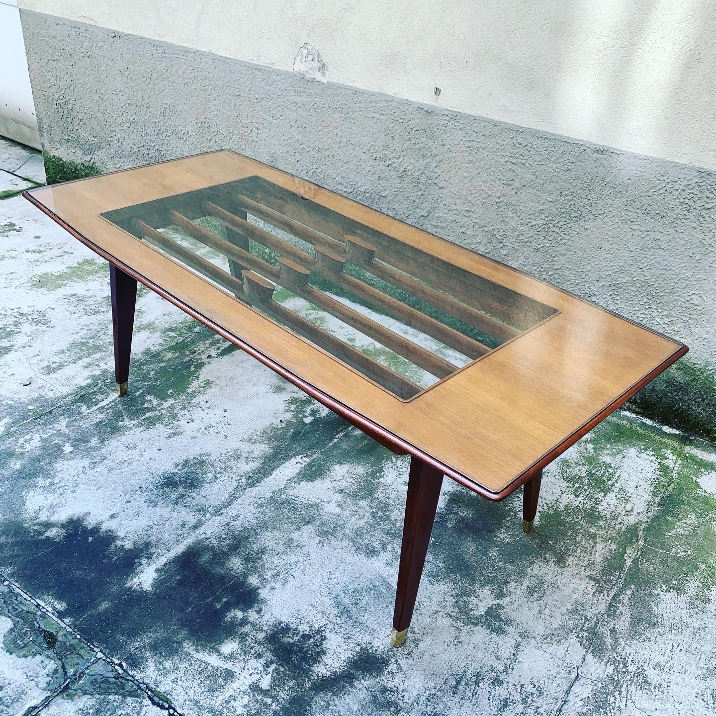Beautiful Italian walnut dining table with brass feet, clear glass top framing an open solid wood decoration.

The table has been completely restored and polished.