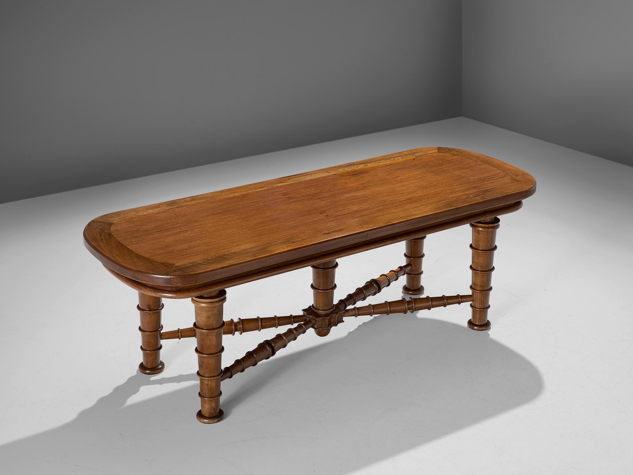 Dining table, walnut, Italy, 1940s.

This Italian dining table has a rectangular top with rounded corners and a detailed cross-section. The top is framed which highlights the veneered top. Remarkable about this table are the legs. Four legs lift the
