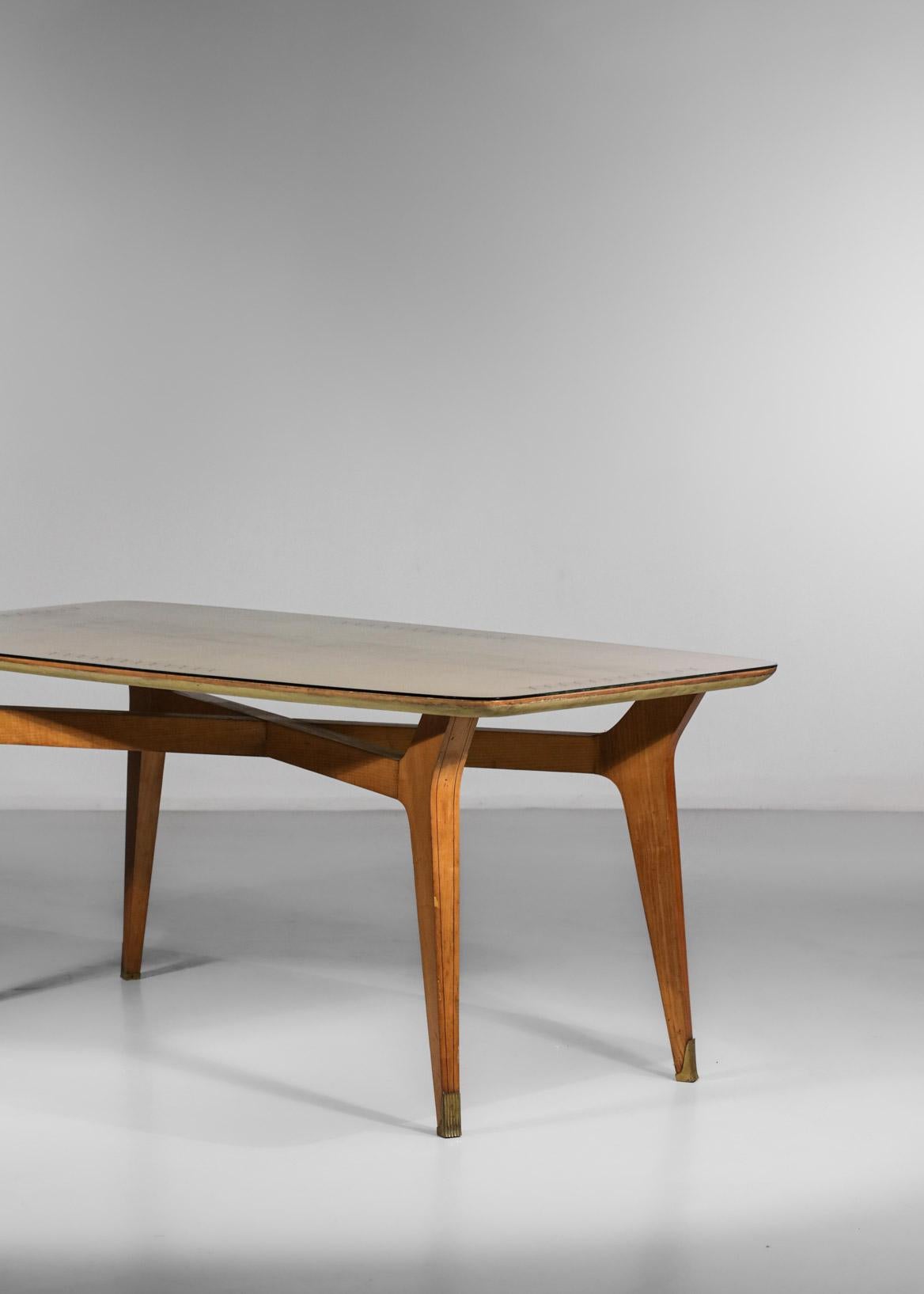 Italian dining table from the 60s. Structure in solid beech and veneer with an acid-etched glass top. Decorated with golden ribbons on each side of the top, the base is finished with a brass piece. Table with sober and elegant lines with nice