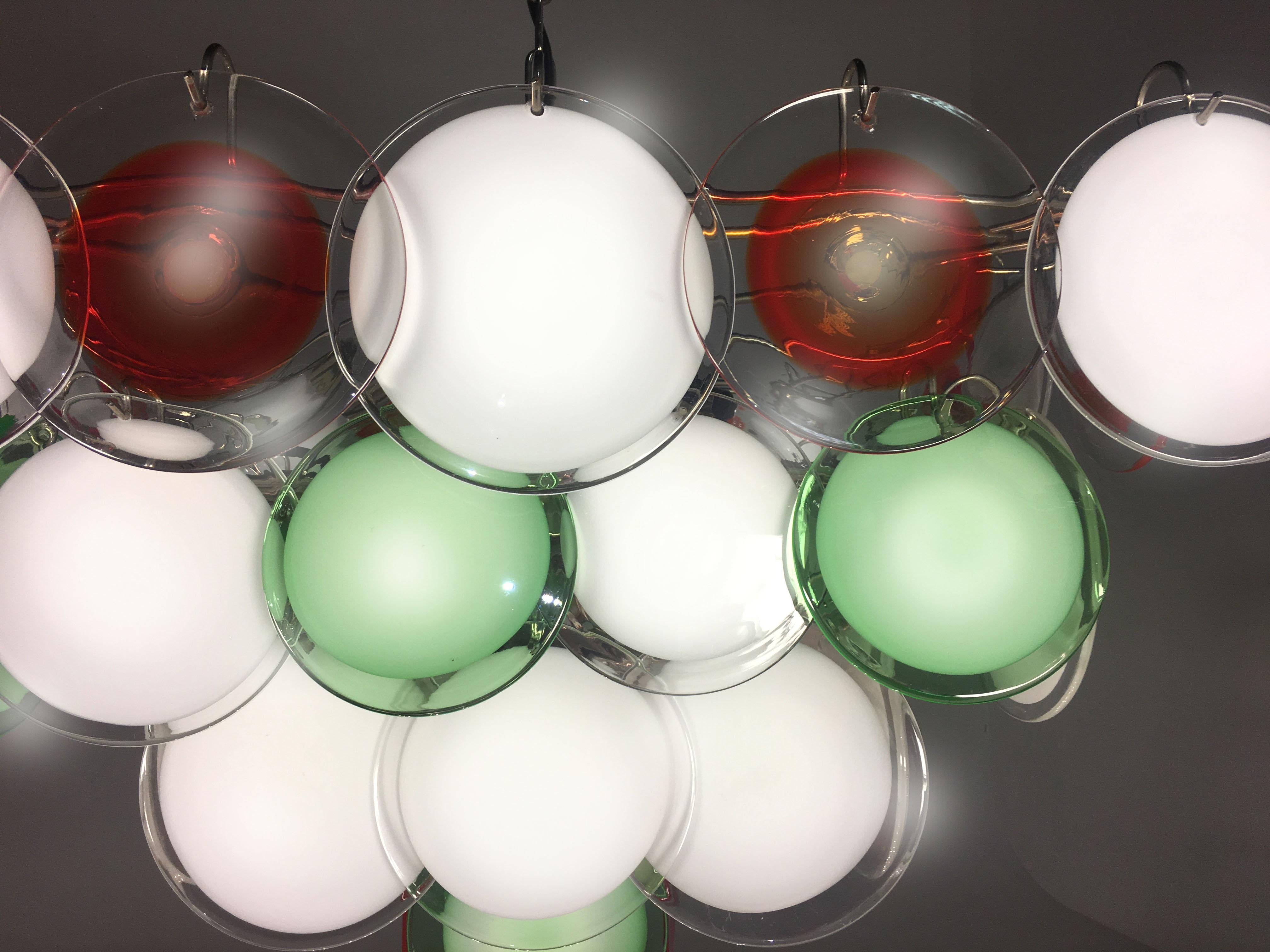 Each chandelier is made of 52 white, red and green discs of precious Murano glass are arranged on four levels. Nine-lights.