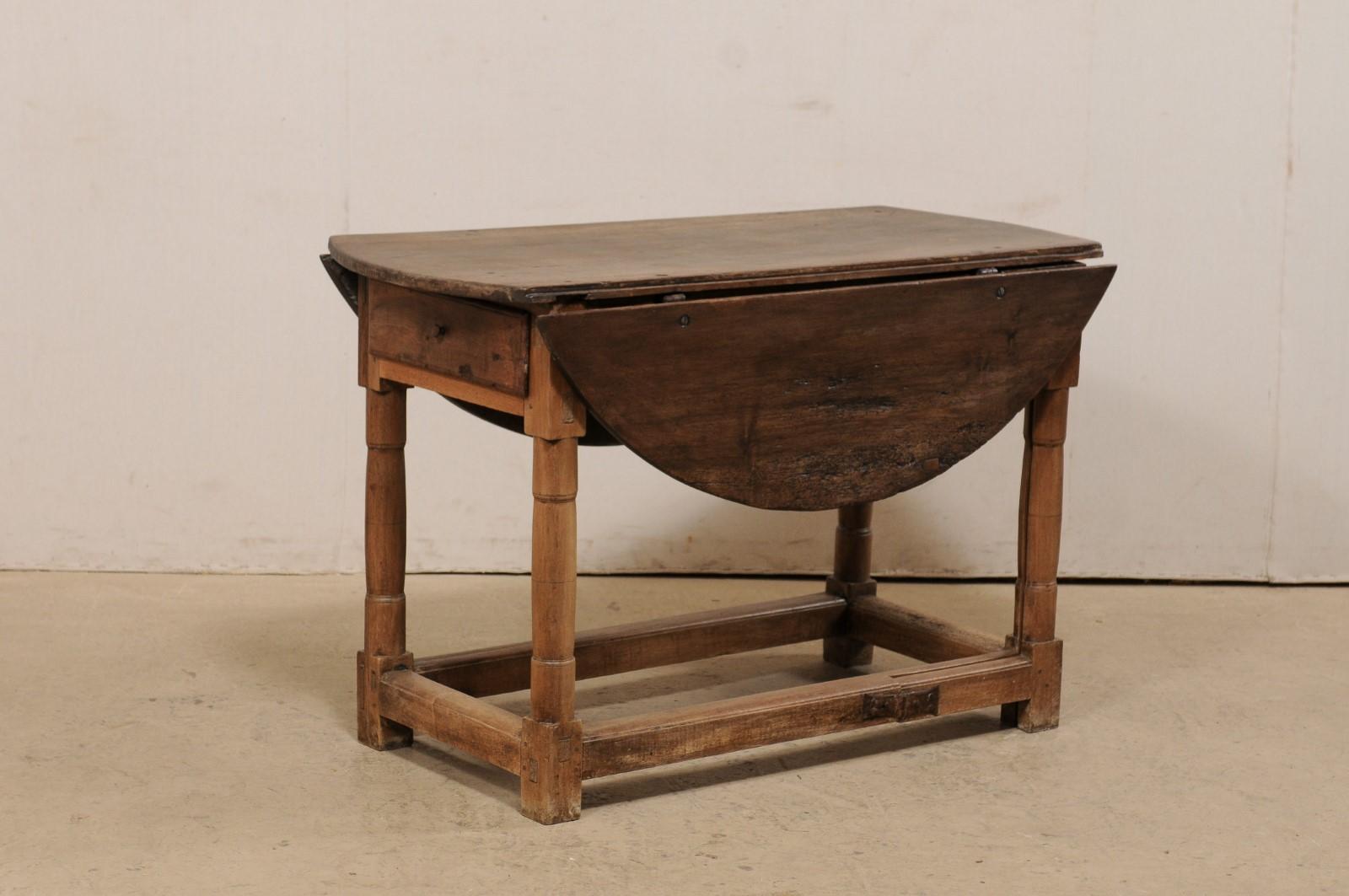 An Italian double gate-leg table from the turn of the 18th and 19th century. This antique table from Italy features a rectangular-shaped center top flanked within two drop leaves along either side, which when raised and supported by the beautifully