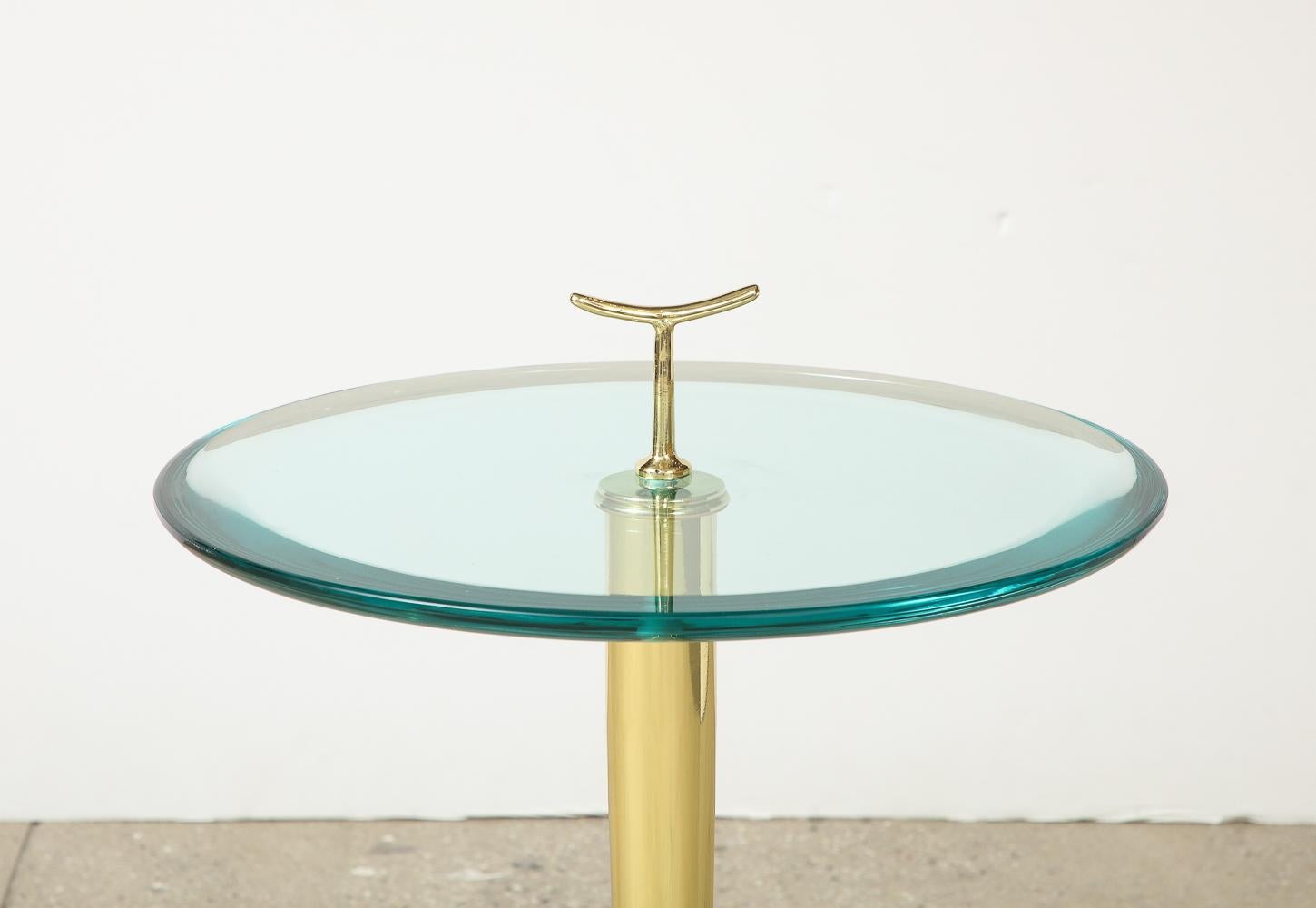 Polished brass structure with 3-pronged foot and stylized finial or handle. Thick, circular glass table surface with elegant beveled edge. Great details throughout.

Dimensions: 
Height of tabletop: 22
