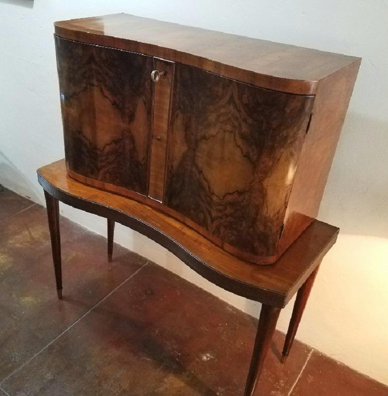 1950s Italian dry bar with an inside light. Inside the bar there is mosaic mirror with three drawers. Inside the doors is stainless steel shelves with glass on the bottom. Base is walnut and possible Rosewood veneer. Both doors wide open, dimension