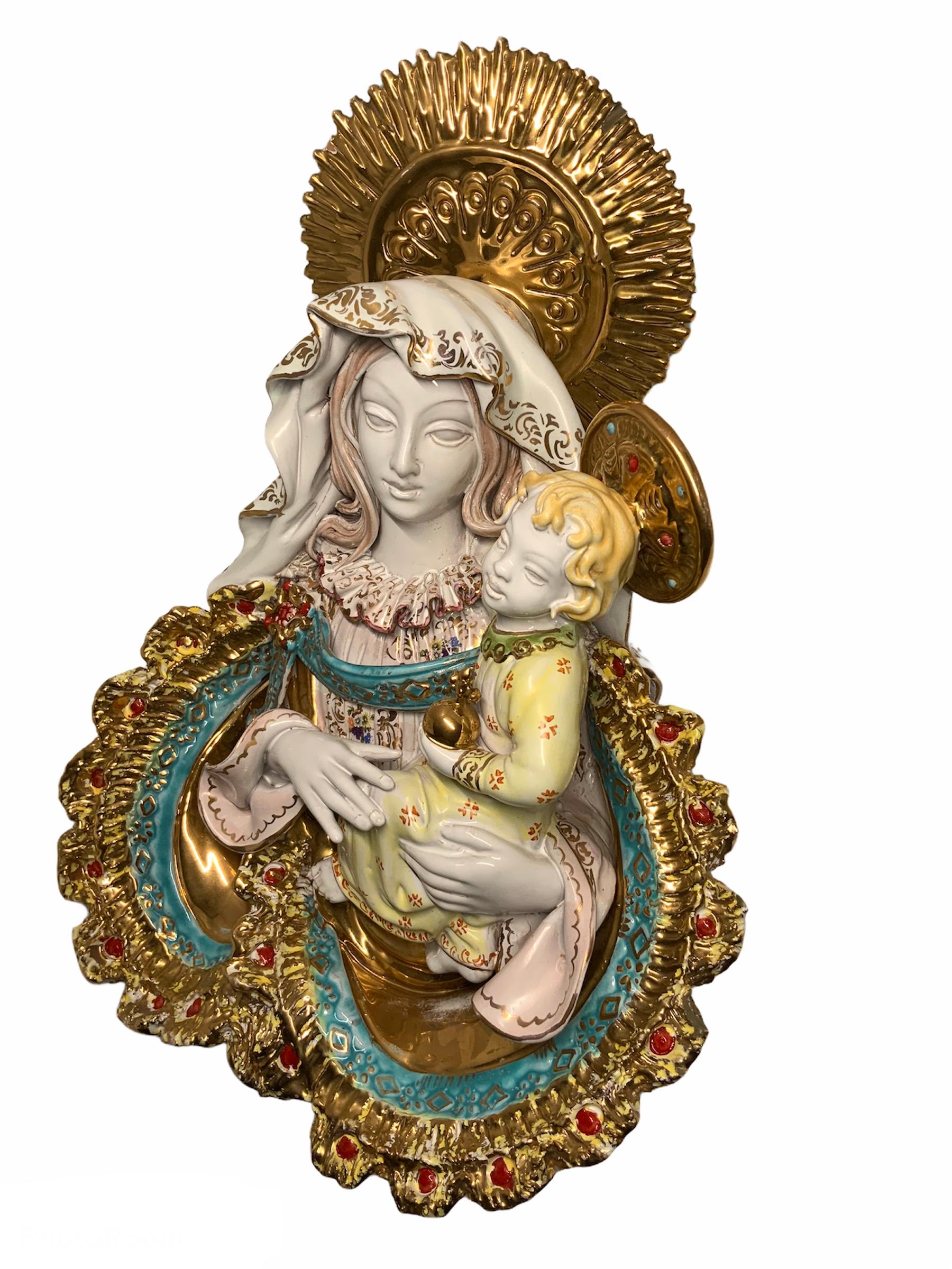 This an Italian E. Pattarino large Madonna and Baby Jesus terra-cotta wall sculpture hand painted in vibrant colors. Both of them adorned with large golden colors crowns. Her pink outfit with ruffles collar is adorned with flowers. Also a gilt