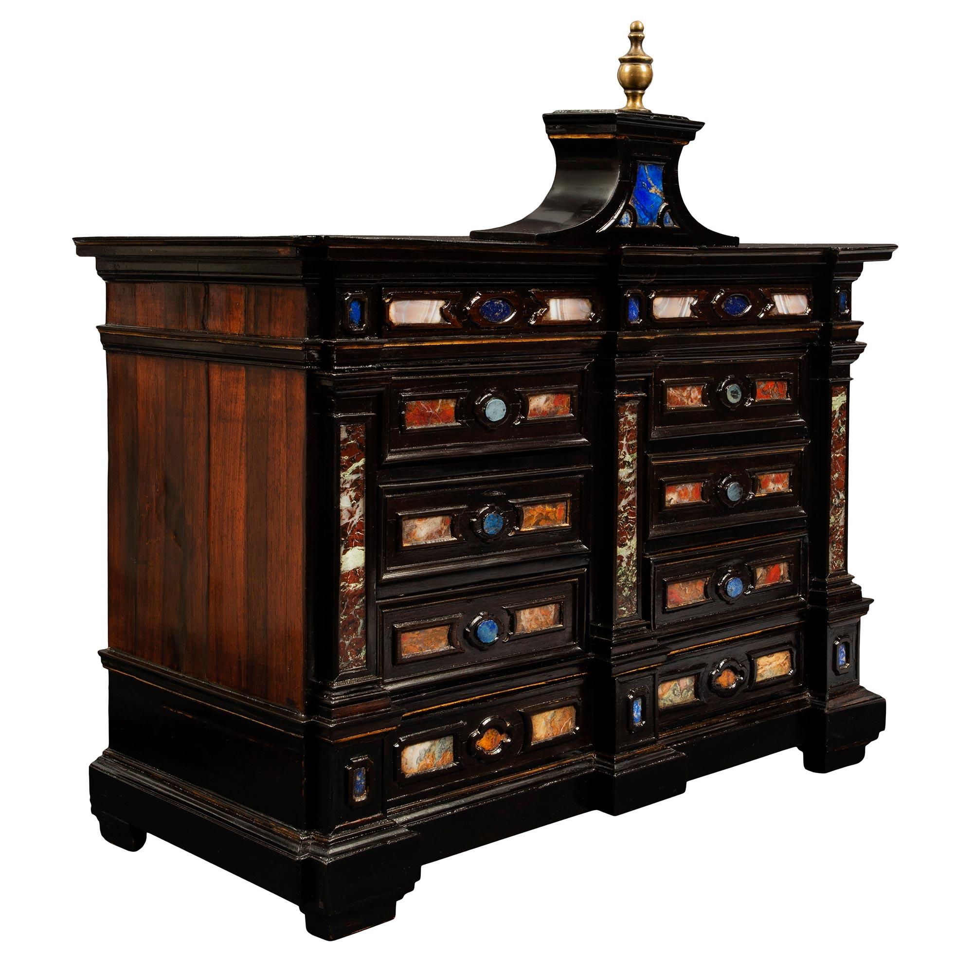 An exceptional and most unique Italian early 18th century Baroque period ebonized fruit wood and Pietra Dura marble and semi precious stone inlaid specimen cabinet. The small scale cabinet is raised by charming block feet below the mottled bottom