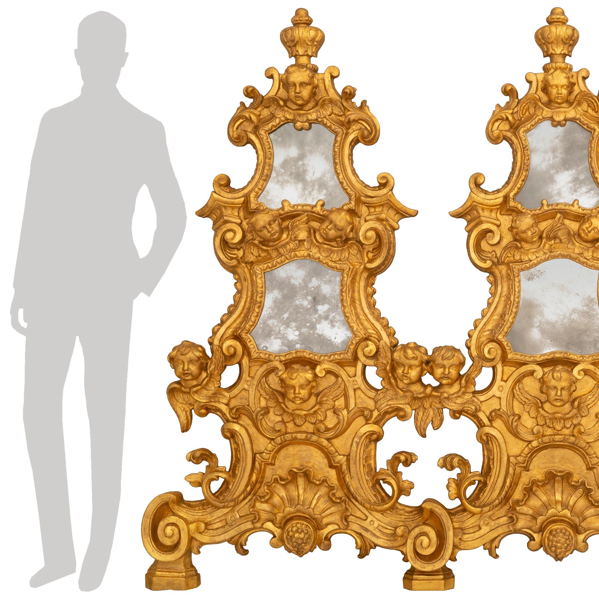 A most unique and impressive Italian early 18th century Baroque st. giltwood triple mirror/wall decor. The remarkable and extremely decorative mirror/wall decor is raised by four mottled block supports below scrolled designs flanking central shell
