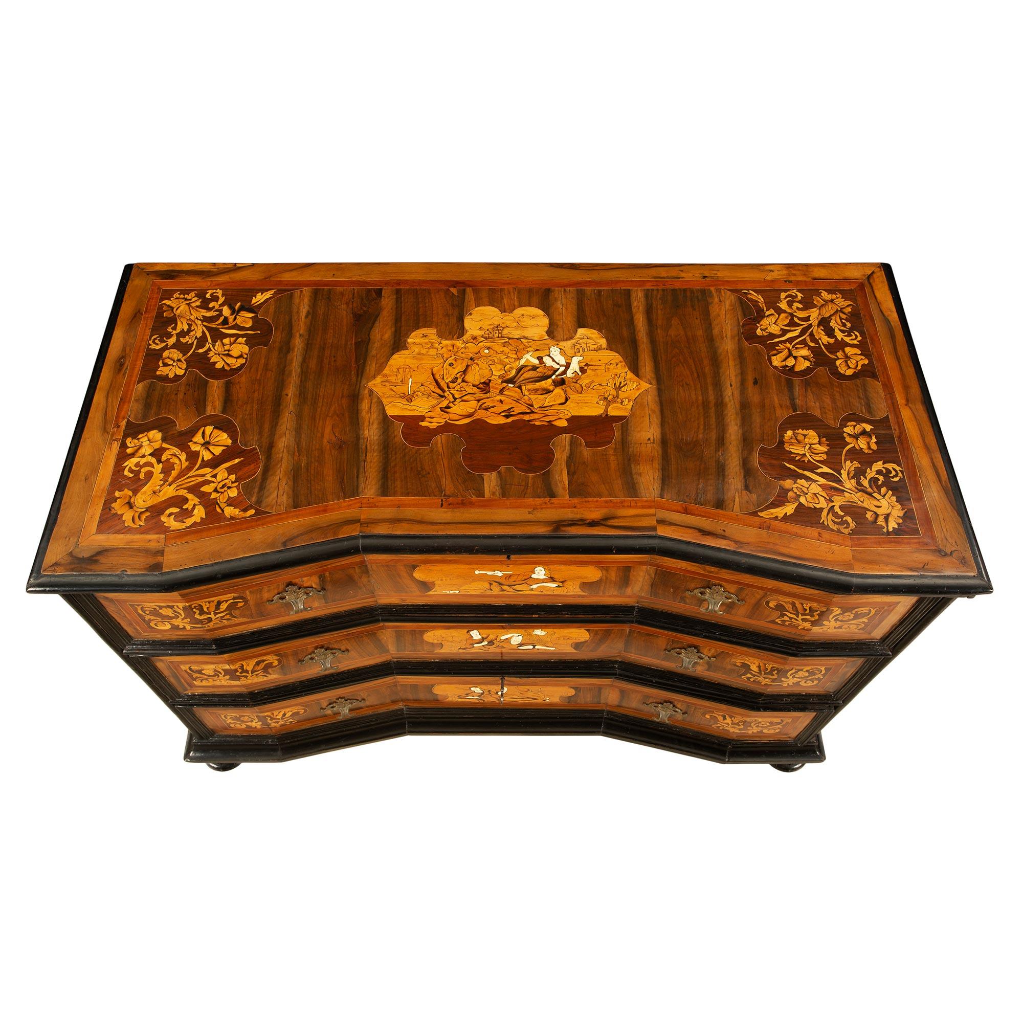 An exceptional Italian early 18th century ebonized fruitwood and walnut inlaid commode from the Lombardi region. This stunning commode is raised on a topie feet below the mottled edge frieze. Above are three very impressive cut angle drawers with