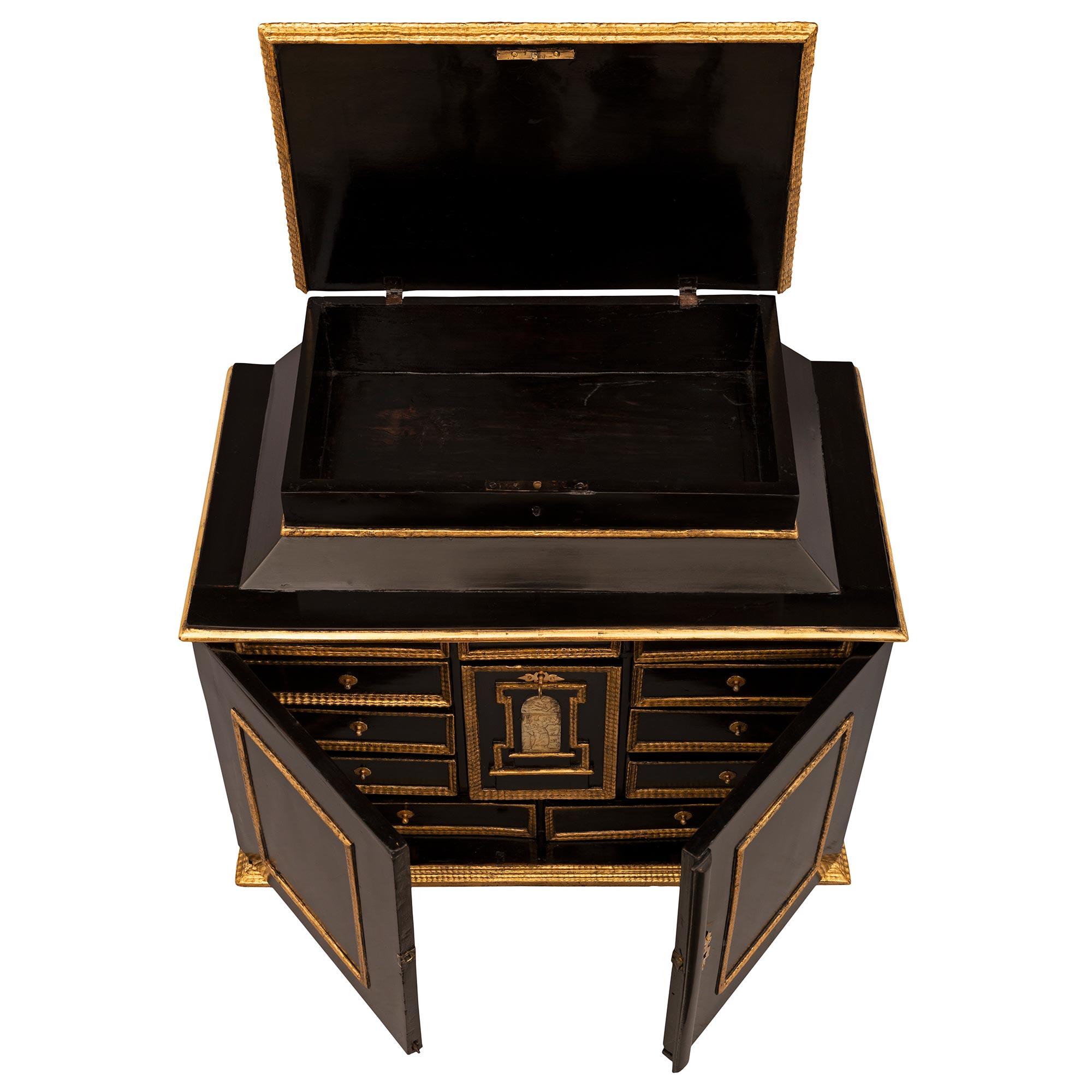 An exceptional and very unique Italian early 18th century Louis XIV period ebonized Fruitwood, bone, giltwood, and gilt metal specimen cabinet. The three door thirteen drawer cabinet is raised by an elegant mottled giltwood band with a most