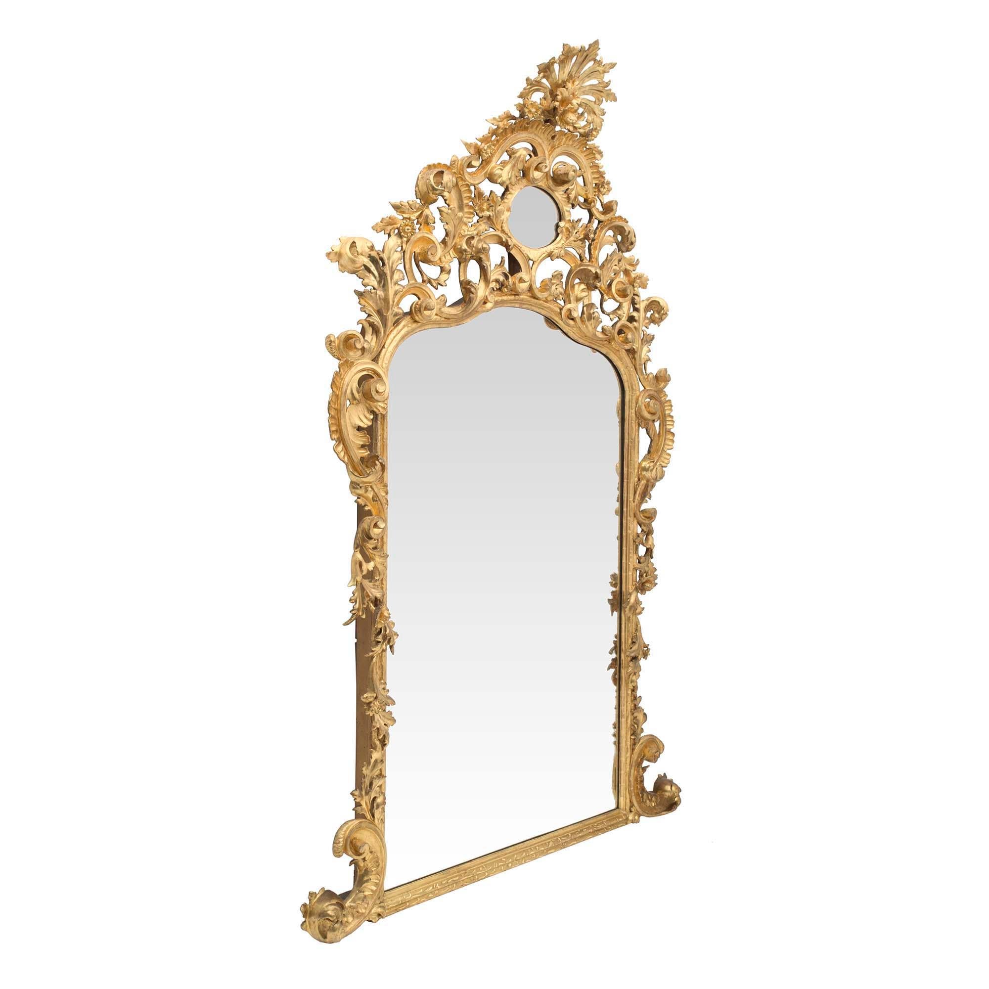 Miroir en bois doré baroque italien du début du XIXe siècle de qualité exceptionnelle et de grande taille. Le bas du miroir présente un cadre moucheté avec des volutes en forme de 