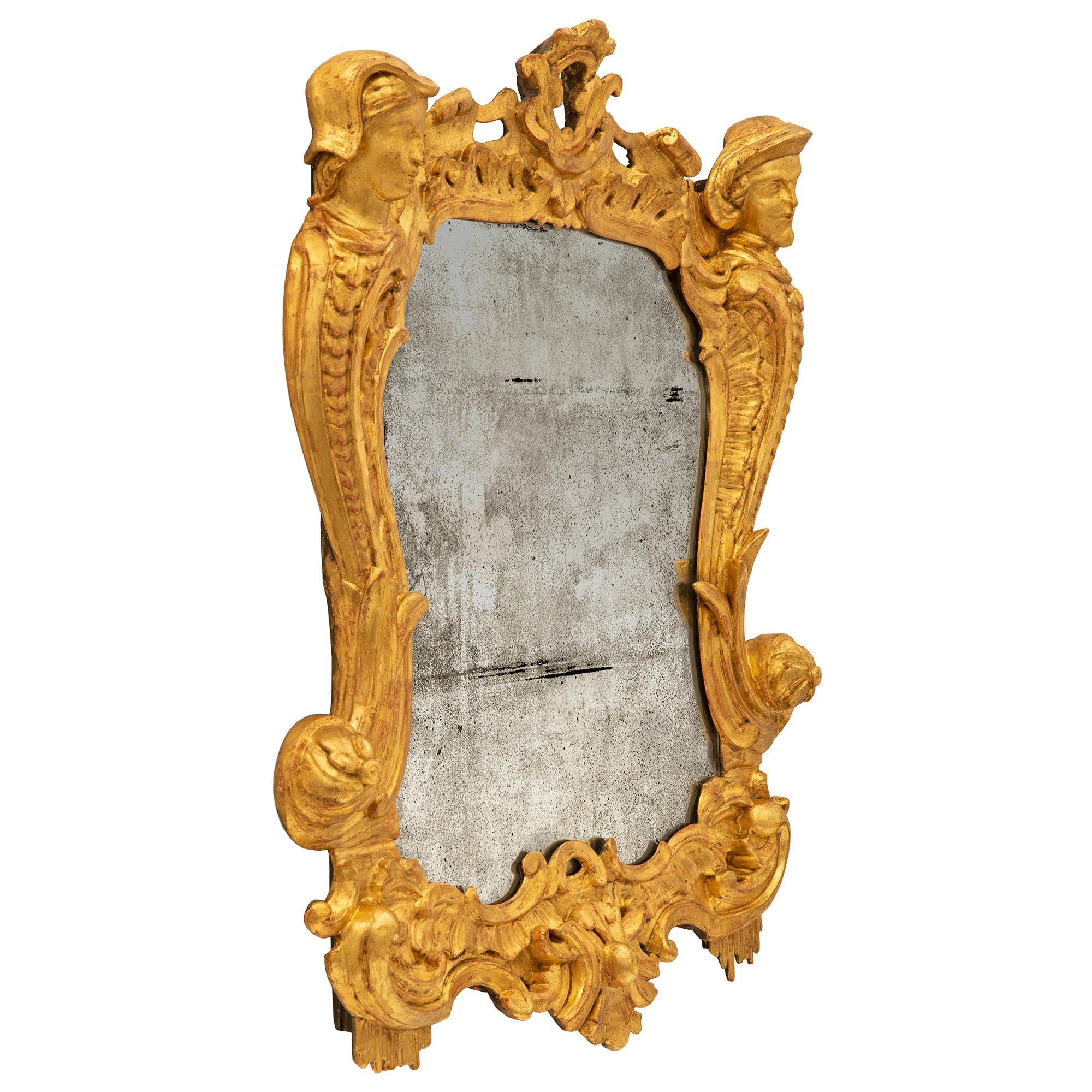 An outstanding Italian early 19th century Baroque st. giltwood mirror. The mirror retains its original mirror plate set within a stunning and extremely decorative giltwood frame. The frame displays beautiful richly carved scrolled foliate designs
