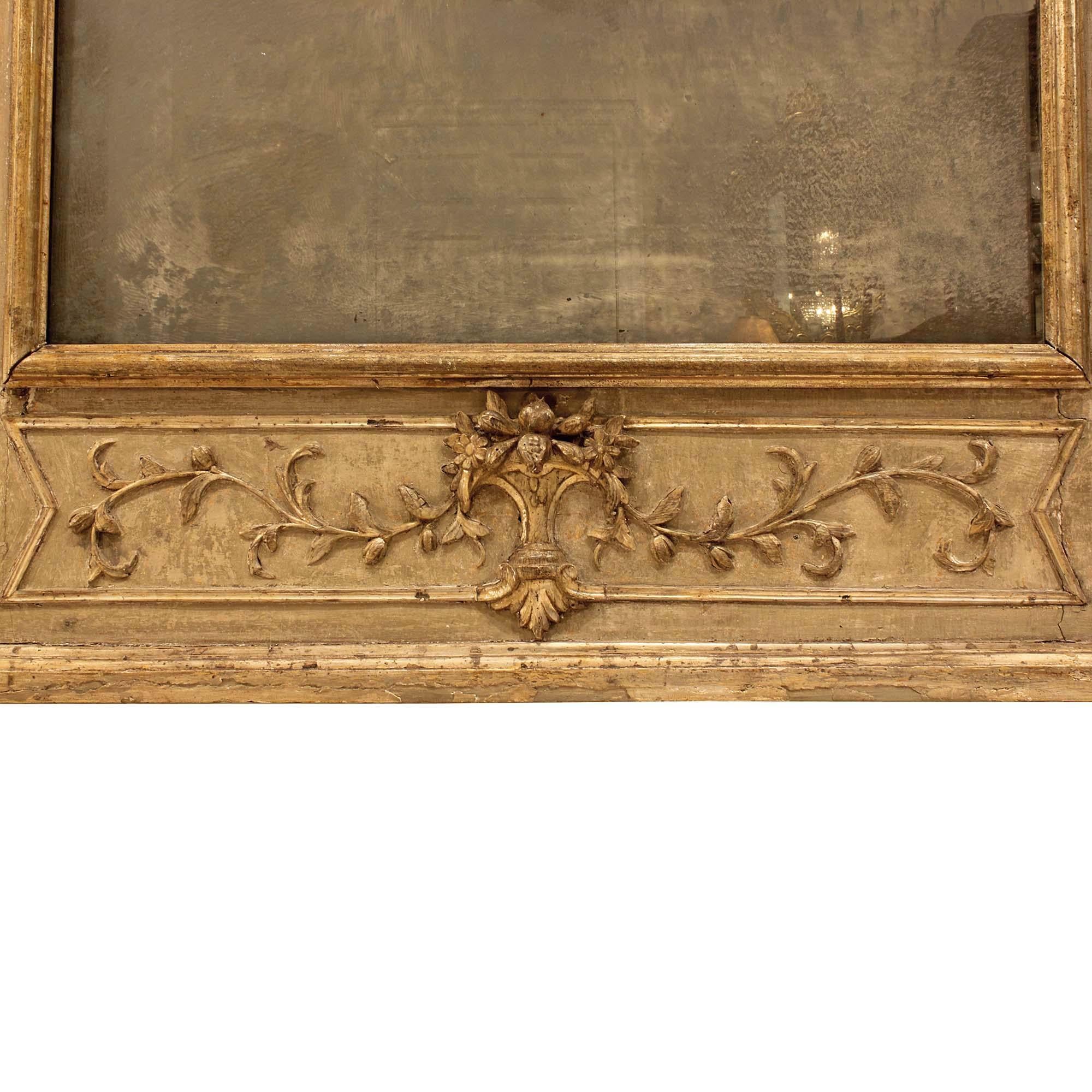 A stunning pair of Italian 18th century Louis XVI period patinated mirrors. Each rectangular mirror has rich carvings throughout and two original mirror plates. The bottom is decorated with a bouquet of flowers and fruit, amidst garlands and flanked