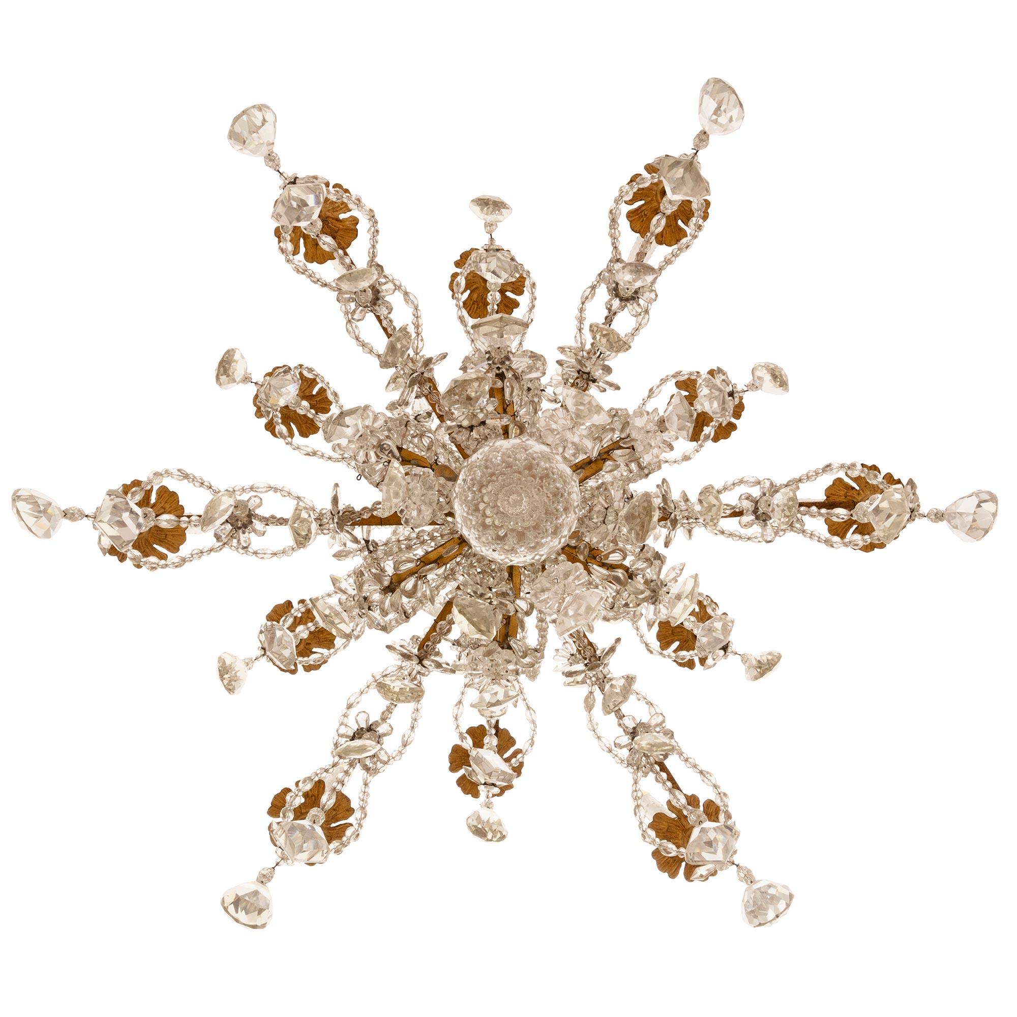 An extremely elegant and high quality Italian early 19th century crystal chandelier from the Turin region. The chandelier has twelve lights on two levels centered at the bottom by a crystal ball pendant. Each elaborately scrolled gilt metal arm is