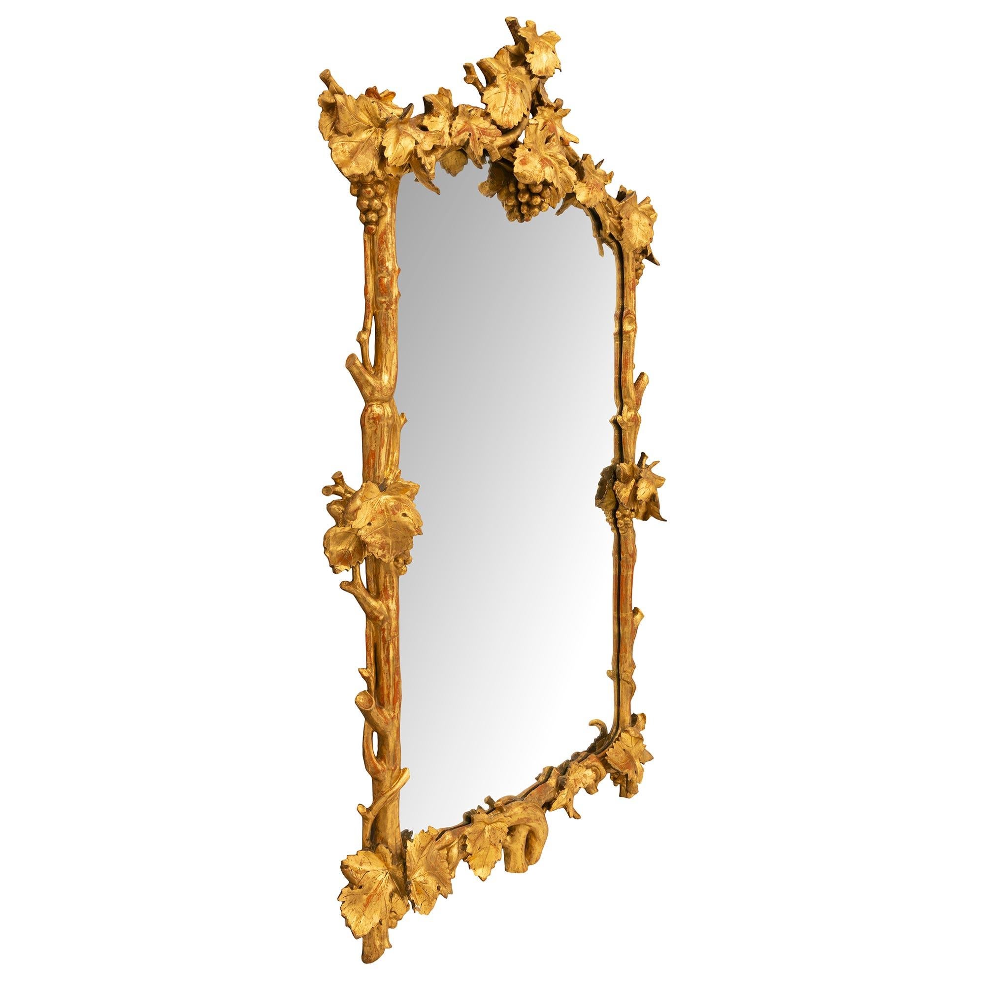 A lovely and unique Italian early 19th century giltwood mirror. The original mirror plate is framed within a branch like giltwood border with wonderful movement. The bottom is centered by two branches coming together and overlapping with large oak