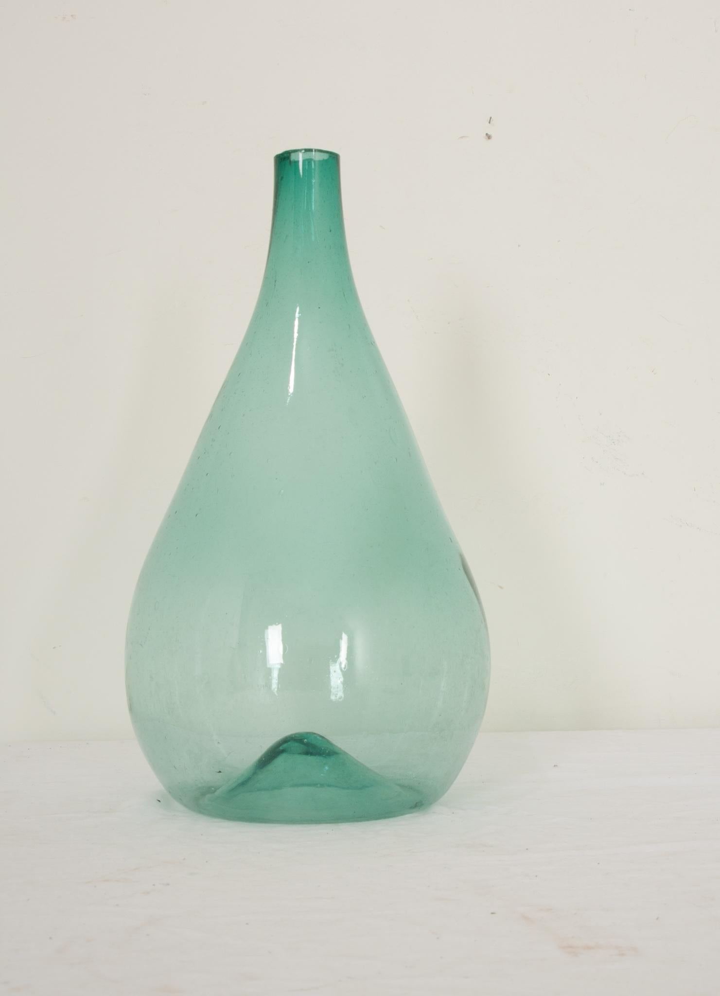 A rare Italian hand blown blue glass damigiana or demijohn hand-crafted in Italy circa 1800. Composed of a gorgeous free-blown aqua blue glass that exhibits trapped air bubbles within the glass and with a sheared lip. Its simply elegant form and