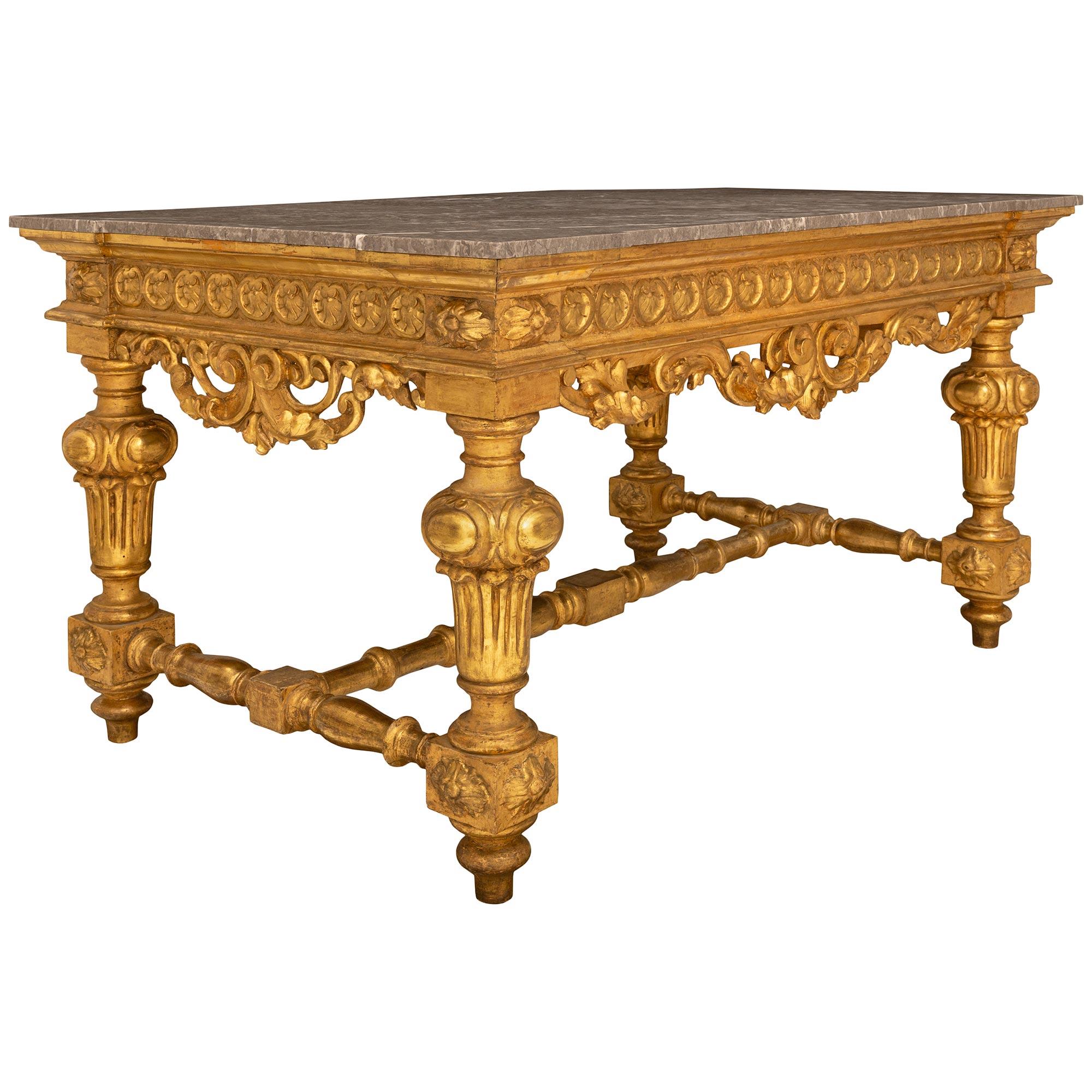 An impressive and large scale Italian early 19th century Louis XIV st. Giltwood and grey marble center table. The rectangular table is finished on all sides and is raised on fine topie shaped supports below the baluster shaped legs decorated with