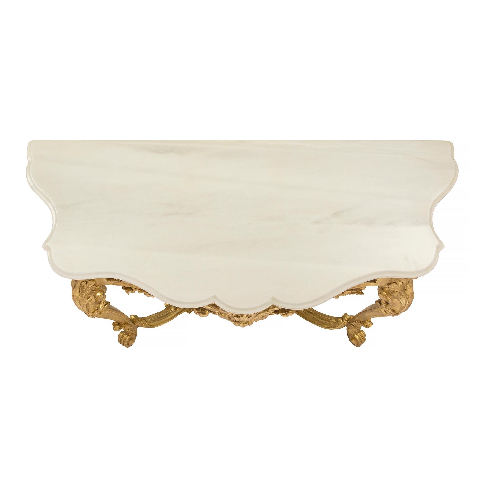 A stunning Italian early 19th century Louis XV st. giltwood and white Carrara marble free standing console. The console is raised by elegant scrolled feet below impressive cabriole legs. Each leg is decorated with large richly carved acanthus