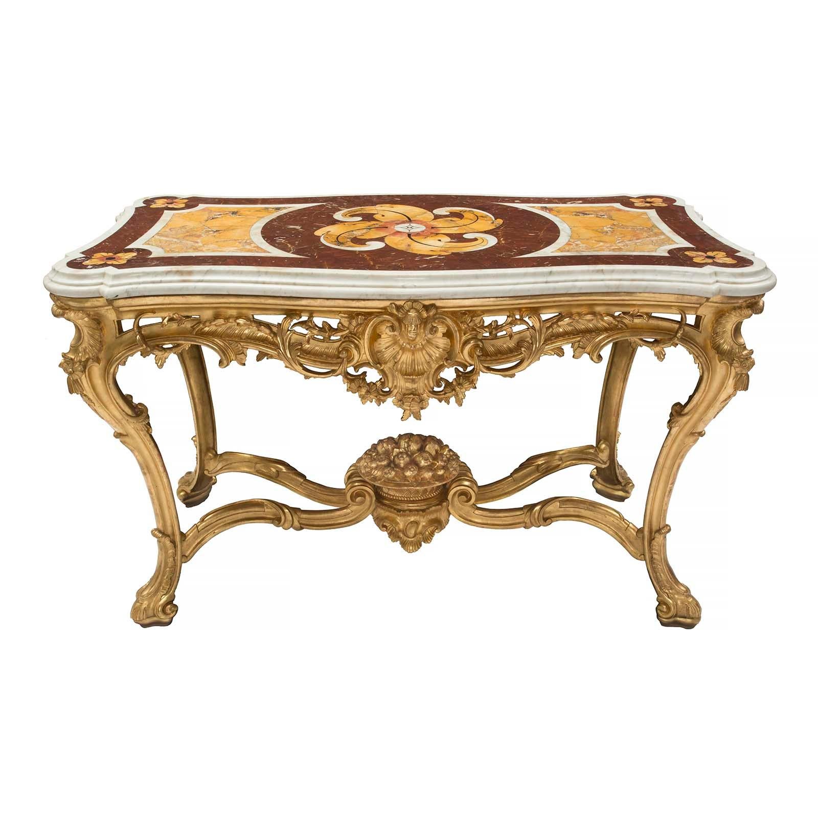 A stunning and high-quality Italian early 19th century Louis XV style giltwood and marble center table. The table is raised by elegantly scrolled legs accented with carved acanthus leaves. The legs are joined by a striking scrolled X-shaped