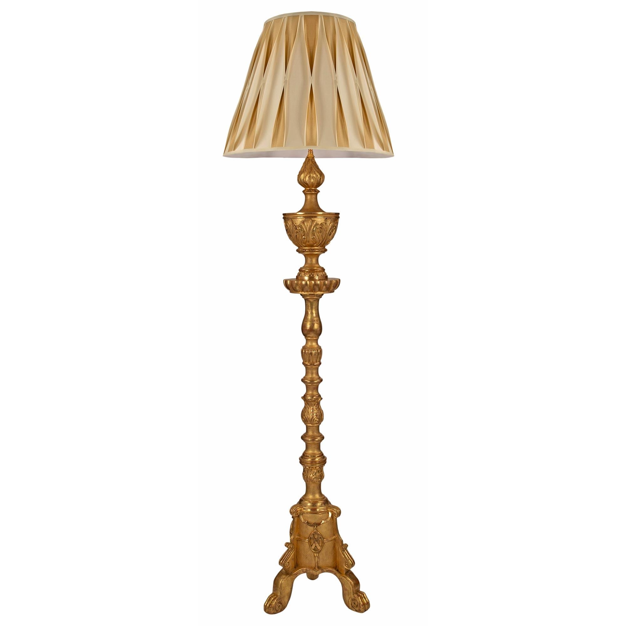 Un très joli lampadaire italien du début du 19ème siècle en bois doré de style Louis XV/XVI. La lampe est surélevée par une base tripode avec des pieds cabriole sous une volute mouchetée. La colonne comporte un écusson central avec un 