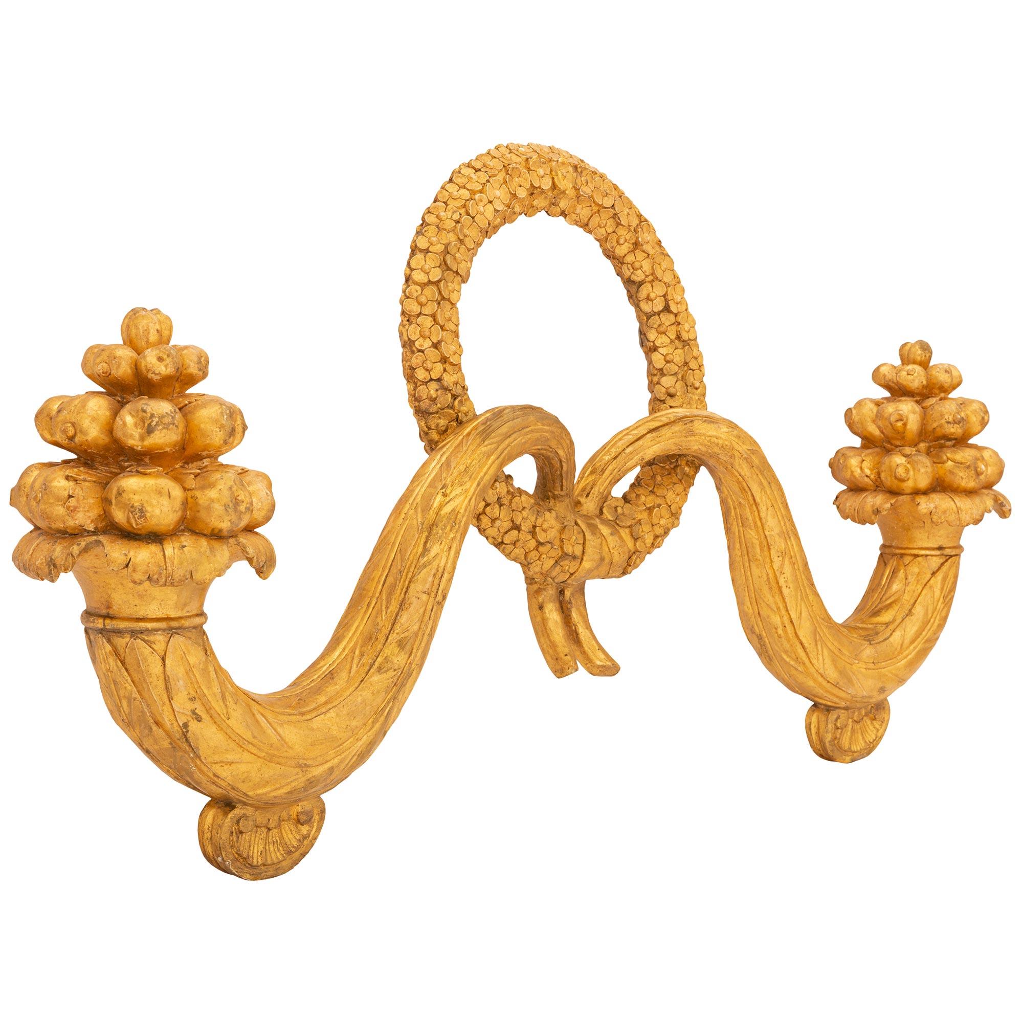 An exceptional and extremely decorative Italian early 19th century Louis XVI st. giltwood decorative wall decor. The wall decor is centered by a beautiful richly carved tied blooming flower wreath. Leading out from the center are two elegantly
