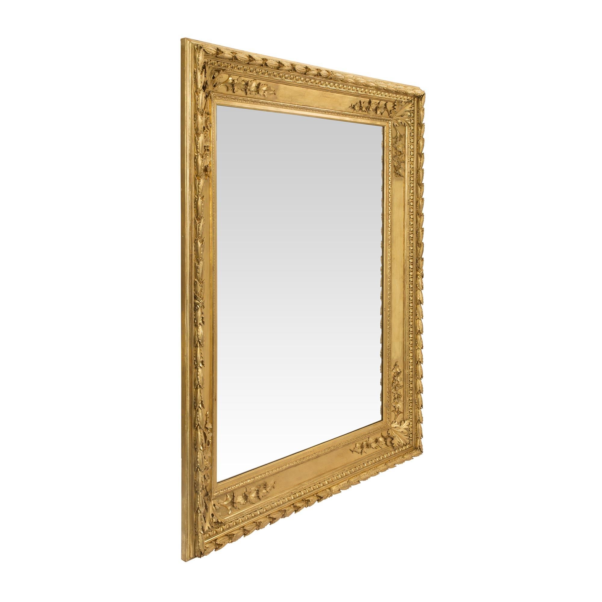 A striking Italian early 19th century Louis XVI st. giltwood mirror. The mirror displays a beautiful and richly carved frame with a Fine foliate border. At each corner are charming grape leaves and bunches of grapes. This mirror can be displayed