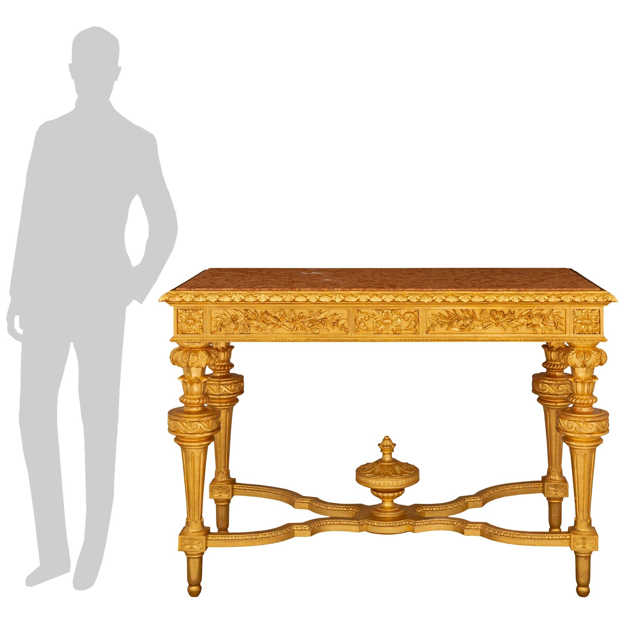Un'imponente e decoratissima consolle italiana di inizio Ottocento in legno di gilt e marmo Rosso Verona. Questa bellissima consolle indipendente con doratura originale e piano in marmo è sollevata da quattro gambe scanalate affusolate che poggiano