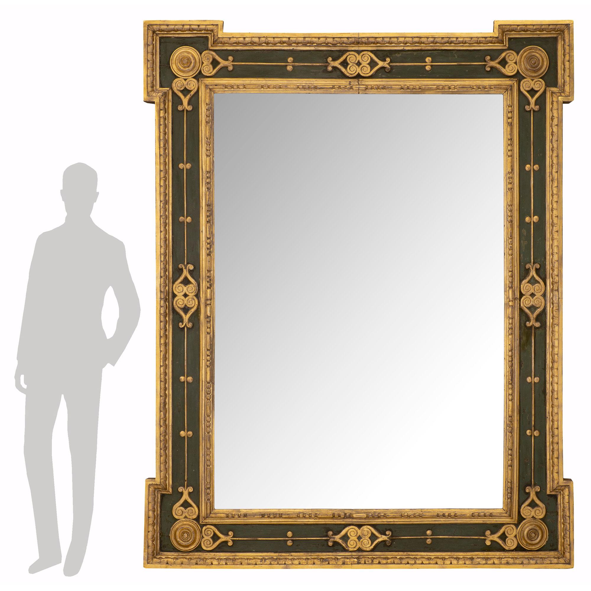 Un miroir italien du début du 19ème siècle en bois patiné et doré de style Louis XVI, très impressionnant et de taille monumentale. La plaque centrale du miroir est insérée dans une belle bande de bois doré moucheté et perlé très décorative. Le