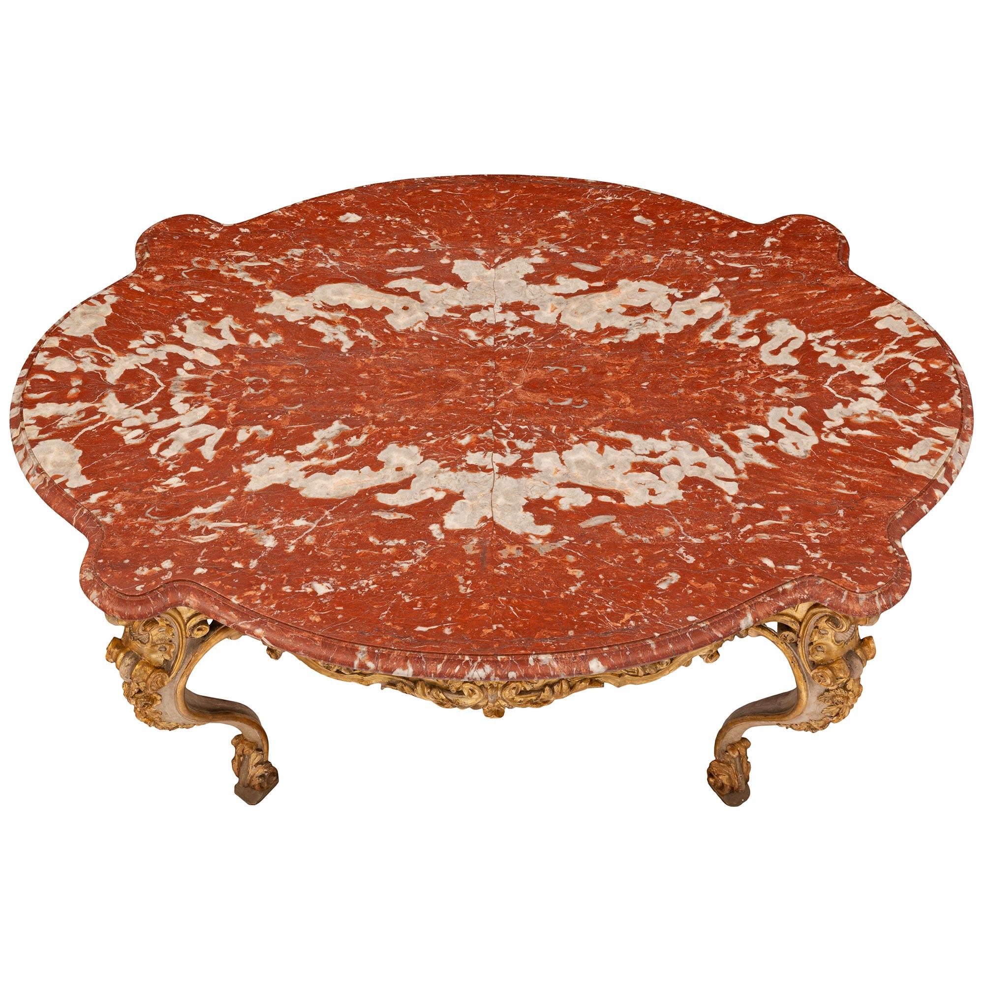 A superb Italian early 19th century Louis XV st. mecca, patinated, and veneered marble top center table. Raised on patinated off white cabriole legs with scrolled mecca trim and ornate with an acanthus leaf at the bottom. At the top of the leg, a