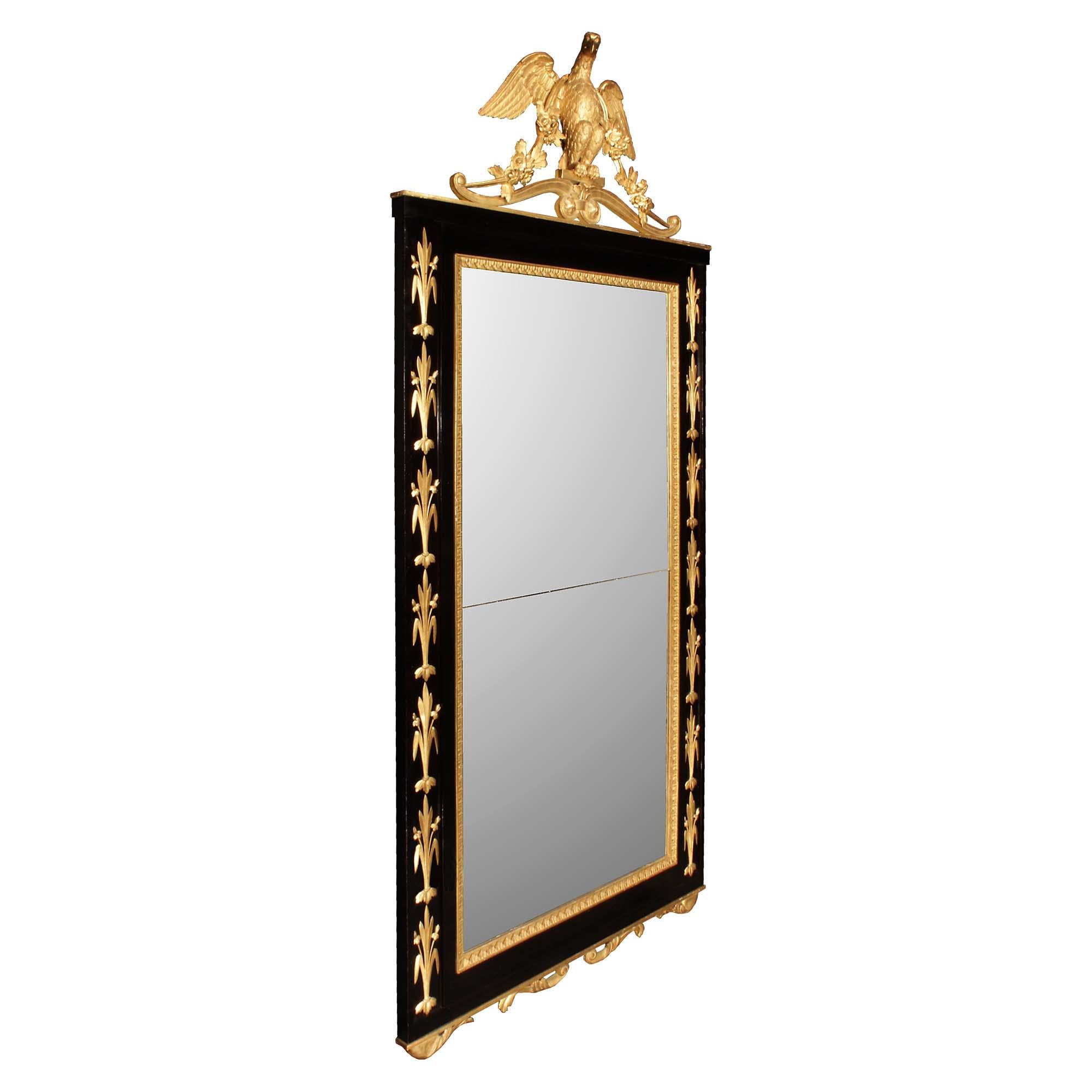 Superbe miroir italien néo-classique du début du XIXe siècle en ébène et bois doré. La plaque de miroir originale se trouve dans un cadre en ébène avec une bordure florale en bois doré sculpté, et un panneau en retrait de chaque côté présentant des