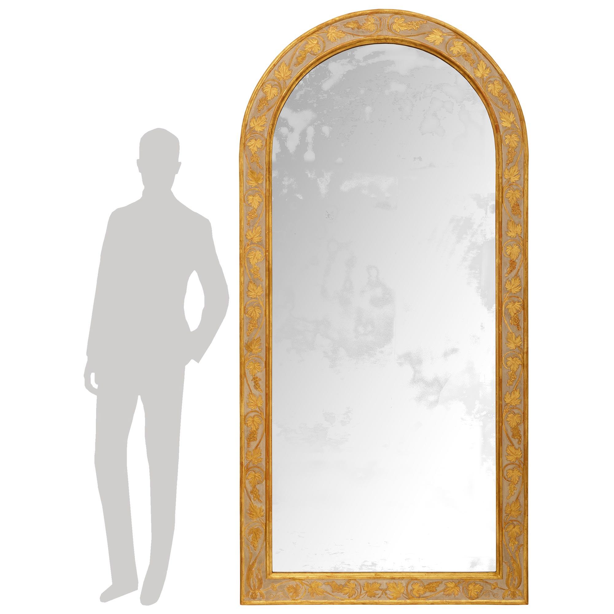 Elegante e molto decorativa specchiera italiana del primo Ottocento in legno patinato e Wood Wood. Questo meraviglioso specchio ad arco è incastonato in una cornice patinata di colore bianco/grigio. La cornice presenta un'elegante vite centrale