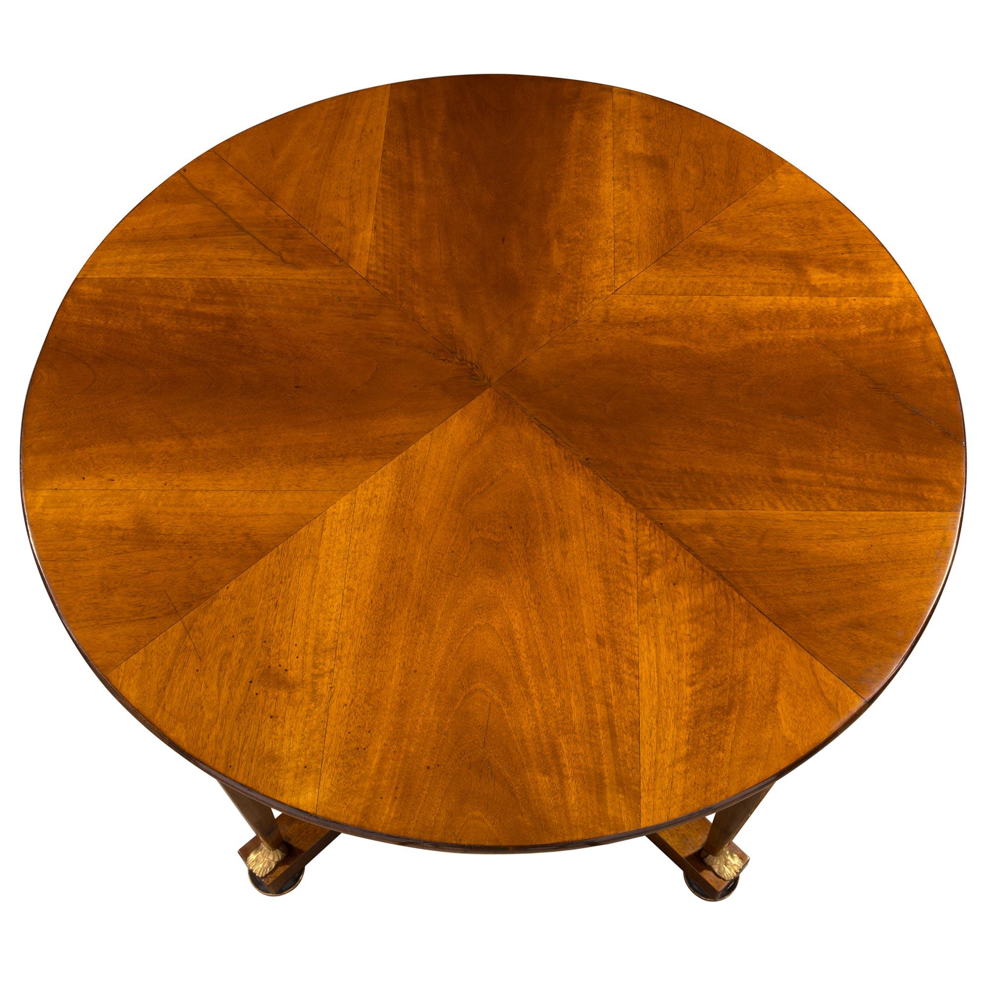 A handsome Italian early 19th century neoclassical walnut, ebonized Fruitwood, ormolu and giltwood circular center table from Lucca. The table is raised by lovely ebonized Fruitwood bun feet with a fine wrap around giltwood band. At the center is