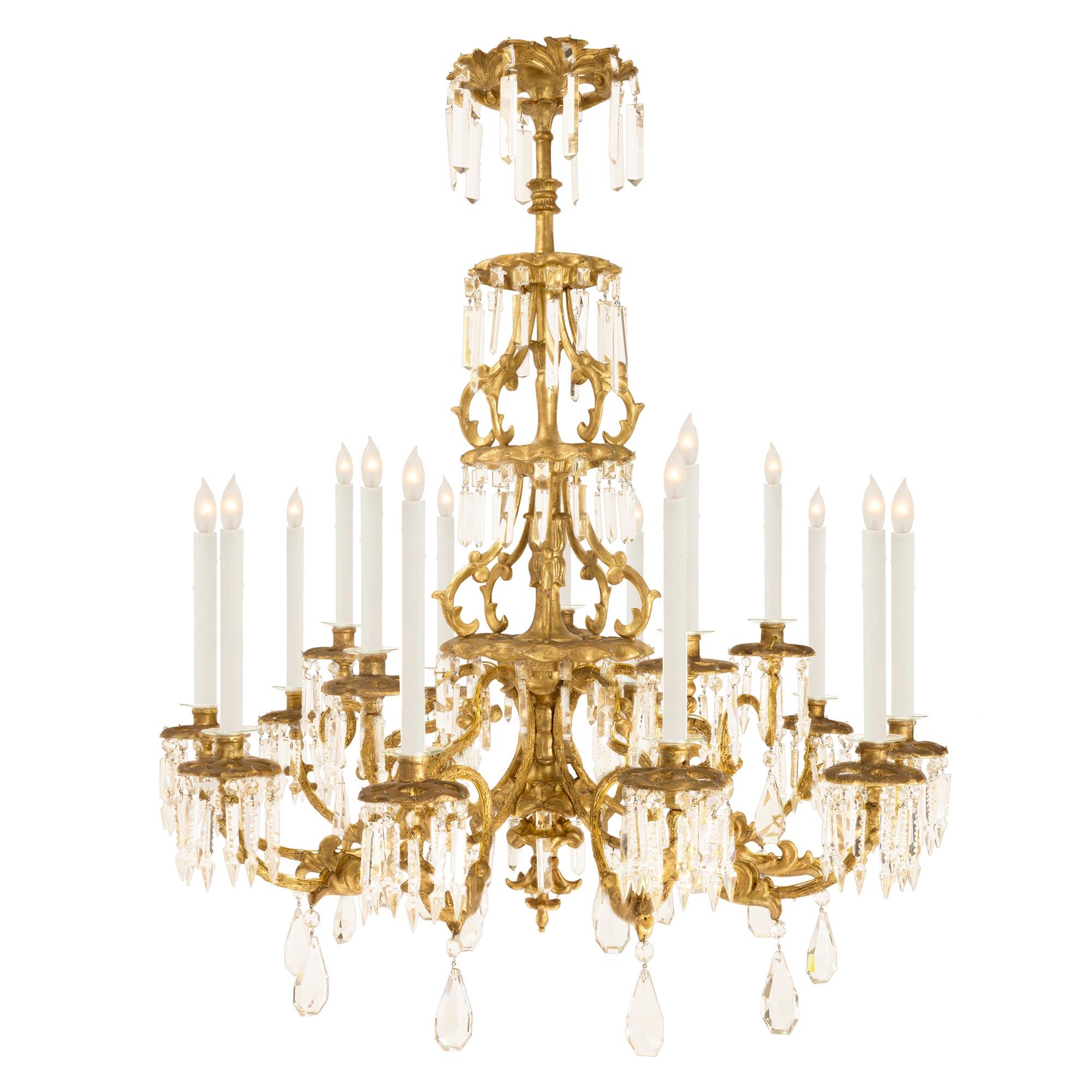 A sensational and unique Italian early 19th century Tuscan giltwood chandelier. The chandelier's fifteen arms are divided among five groups of three electrified candles and split between two tiers. Each arm has a branch like design which leads to a