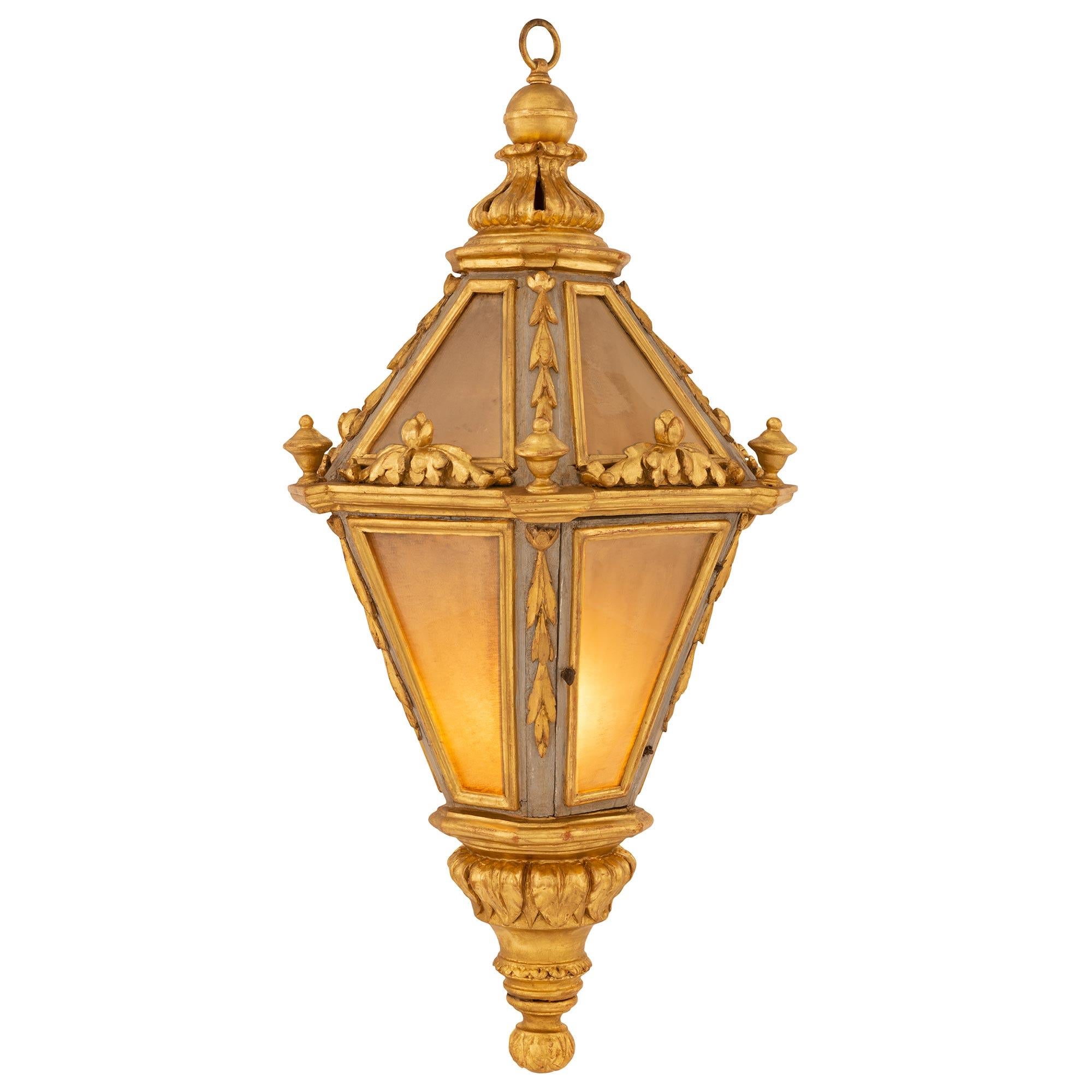 An outstanding Italian early 19th century Venetian st. patinated and giltwood lantern. The lantern is centered by a charming bottom foliate final below lovely richly carved acanthus leaves and foliate designs. The pentagonal shaped body retains its