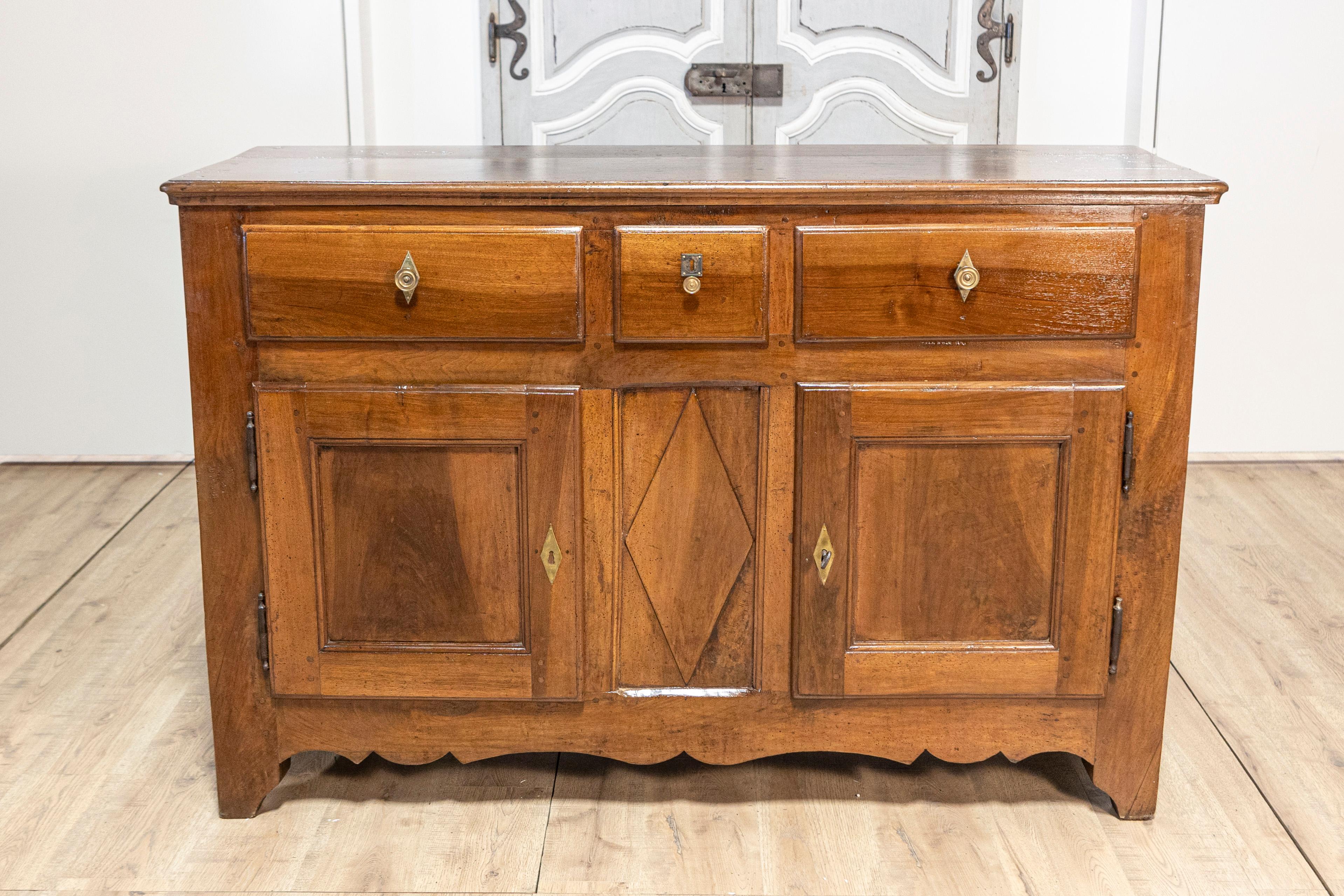 An Italian walnut buffet from the early 19th century, with three drawers over two doors, carved diamond motif and scalloped apron. This exquisite Italian walnut buffet from the early 19th century showcases timeless elegance and meticulous