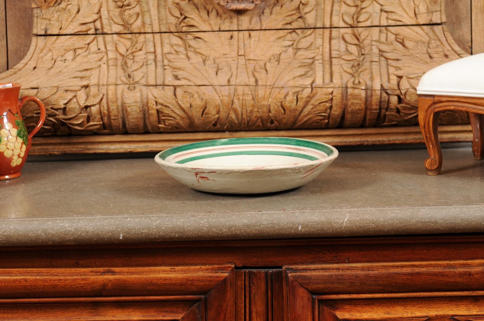 Eine italienische Keramikschale aus dem frühen 20. Jahrhundert mit Hahnmotiv und grünem Rand. Diese in den ersten Jahren des 20. Jahrhunderts in Italien hergestellte Keramikschale bezaubert durch die archaische Darstellung eines Hahns im Profil.