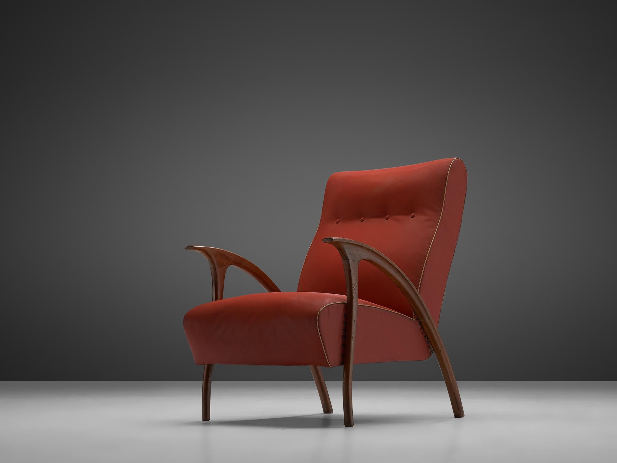 Easy chair, walnut, red leatherette , Italy 1960s.

Beautiful Italian armchair in walnut created in the 1960s. The chair features a gorgeous, sculptural frame with gracious forms. Therefore, the armrests make a grand gesture in their curve. The seat