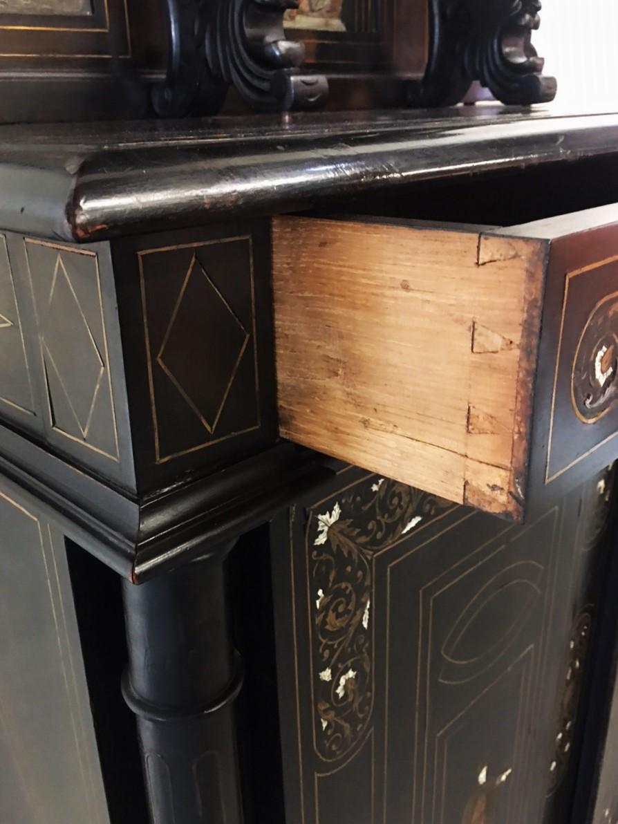 This is an Italian high-back Server or sideboard with an ebonized finish. All inlaid with brass and bone. The string inlays are brass also. The painted panels depict figures in period historic costume.