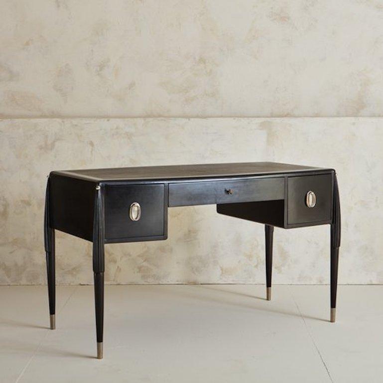 An ebonized maple wood desk with a walnut veneer in the style of Émile-Jacques Ruhlmann. This desk features a black leather inlay top with a hand applied silver leaf trim. It has elegant tapered legs with chrome feet and hand painted silver ball