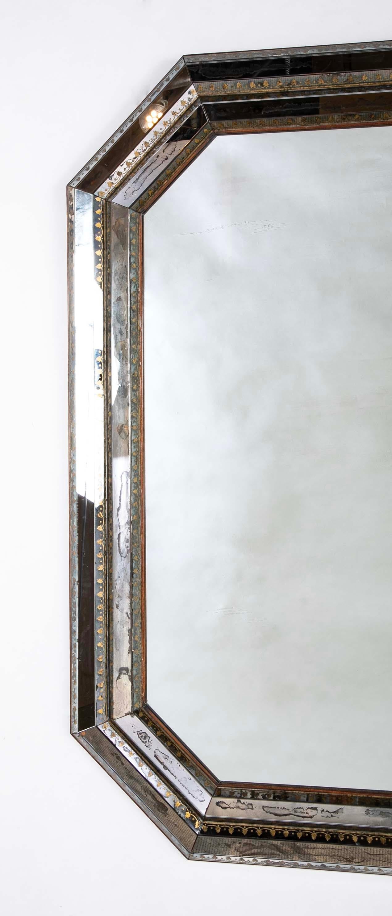 Miroir vénitien octogonal à grande échelle, avec cadre à bandeau en relief, en verre inversé à décor doré, vers 1950. Un bel exemple de design italien du milieu du XXe siècle, qui rappelle le baroque tout en étant tout à fait moderne. Les bandes en