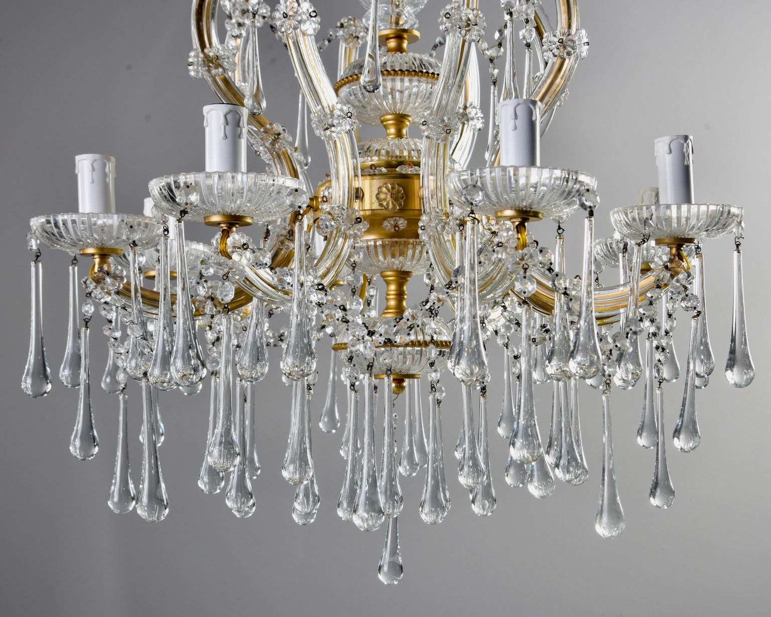 Italian crystal chandelier features eight arms with candle style lights and candelabra sized sockets, etched bobeches, gilded metal frame embellished with etched glass spacers, crystal beading and flowers, circa 1920s. Bobeches and arms are hung
